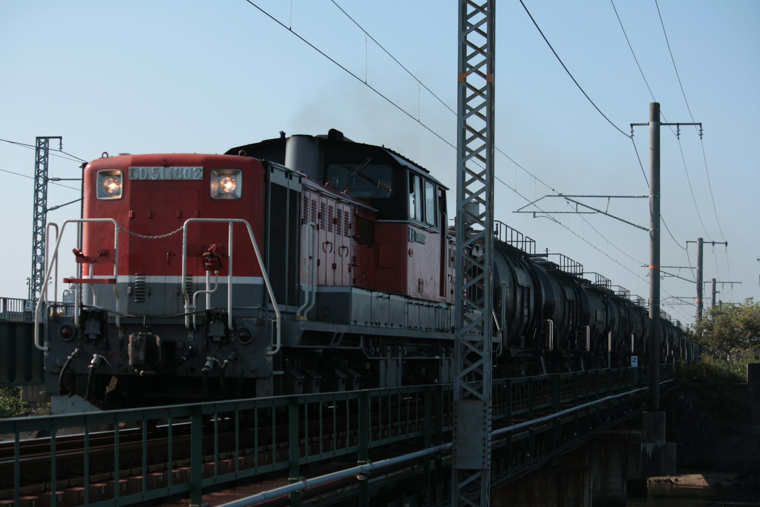 Una locomotora roja que arrastra un tren de carga sobre un puente
