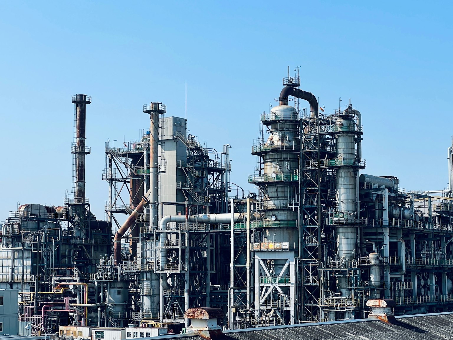 Industrial plant exterior with complex pipes and tanks under bright blue sky