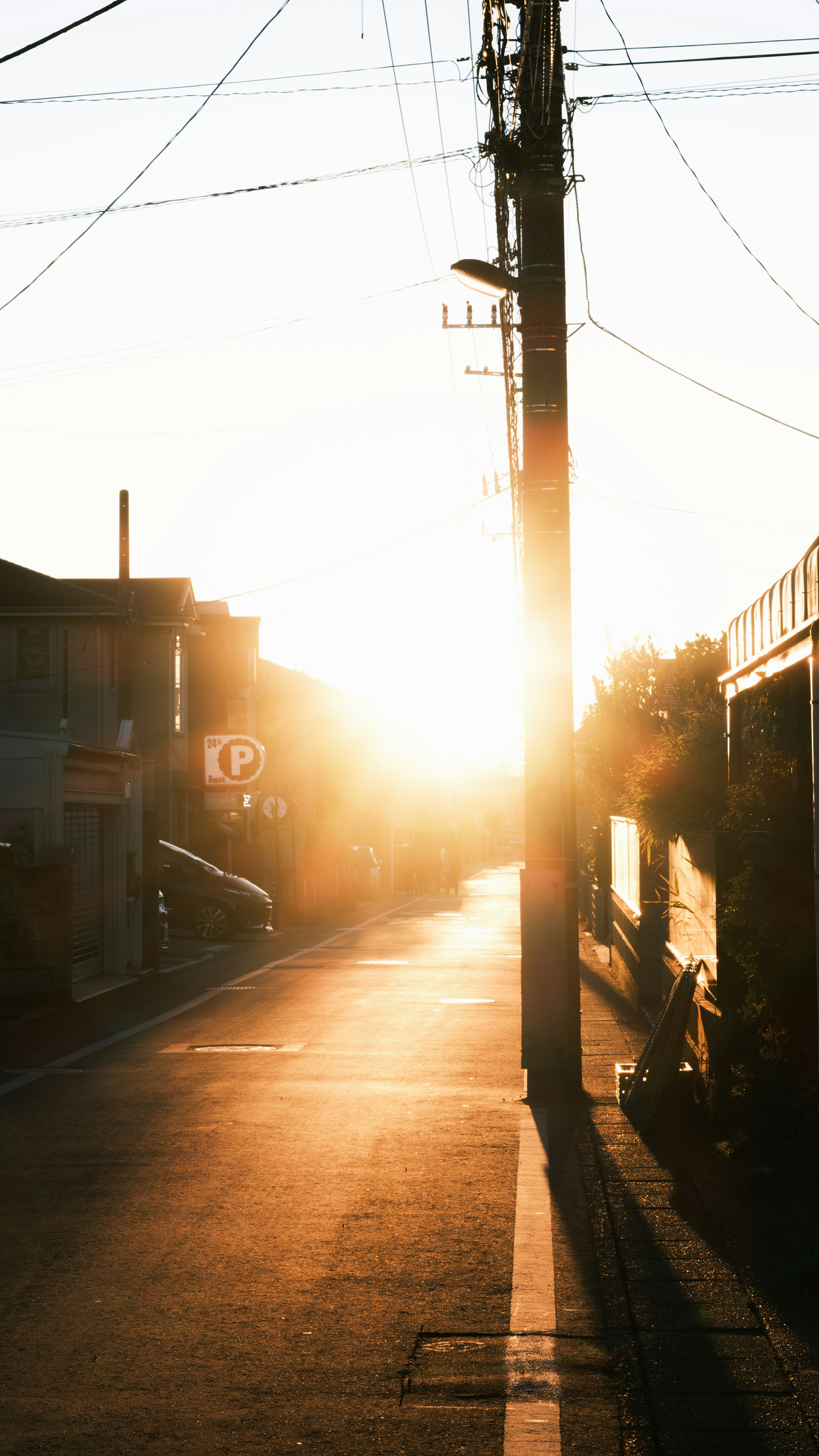 夕日に照らされる路地の電柱と建物の並び