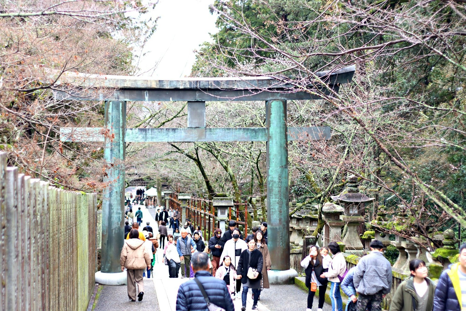 Eine malerische Ansicht mit einem alten bronzenen Torii und Touristen