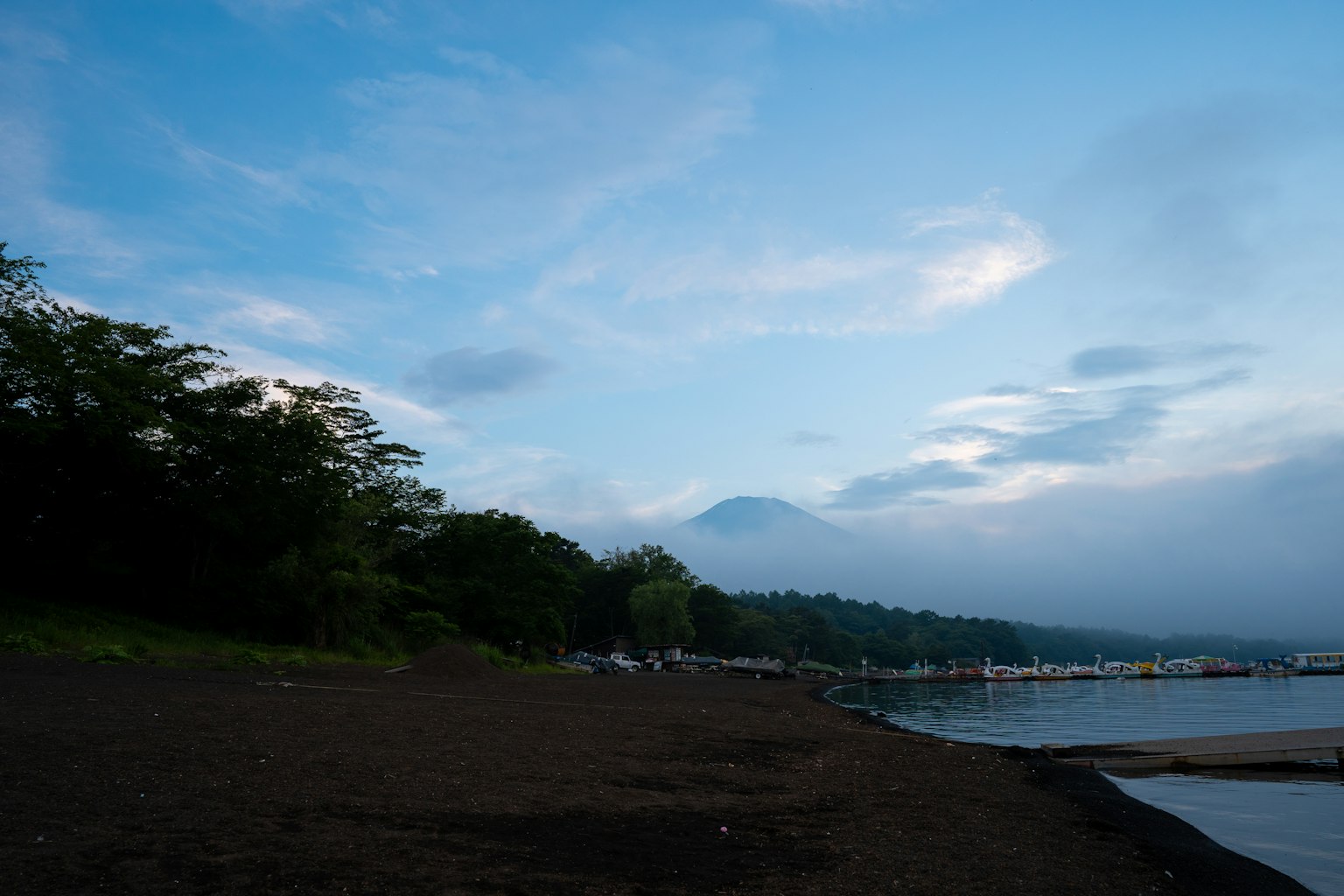 寧靜的湖岸，藍天和雲朵與綠色樹木相伴