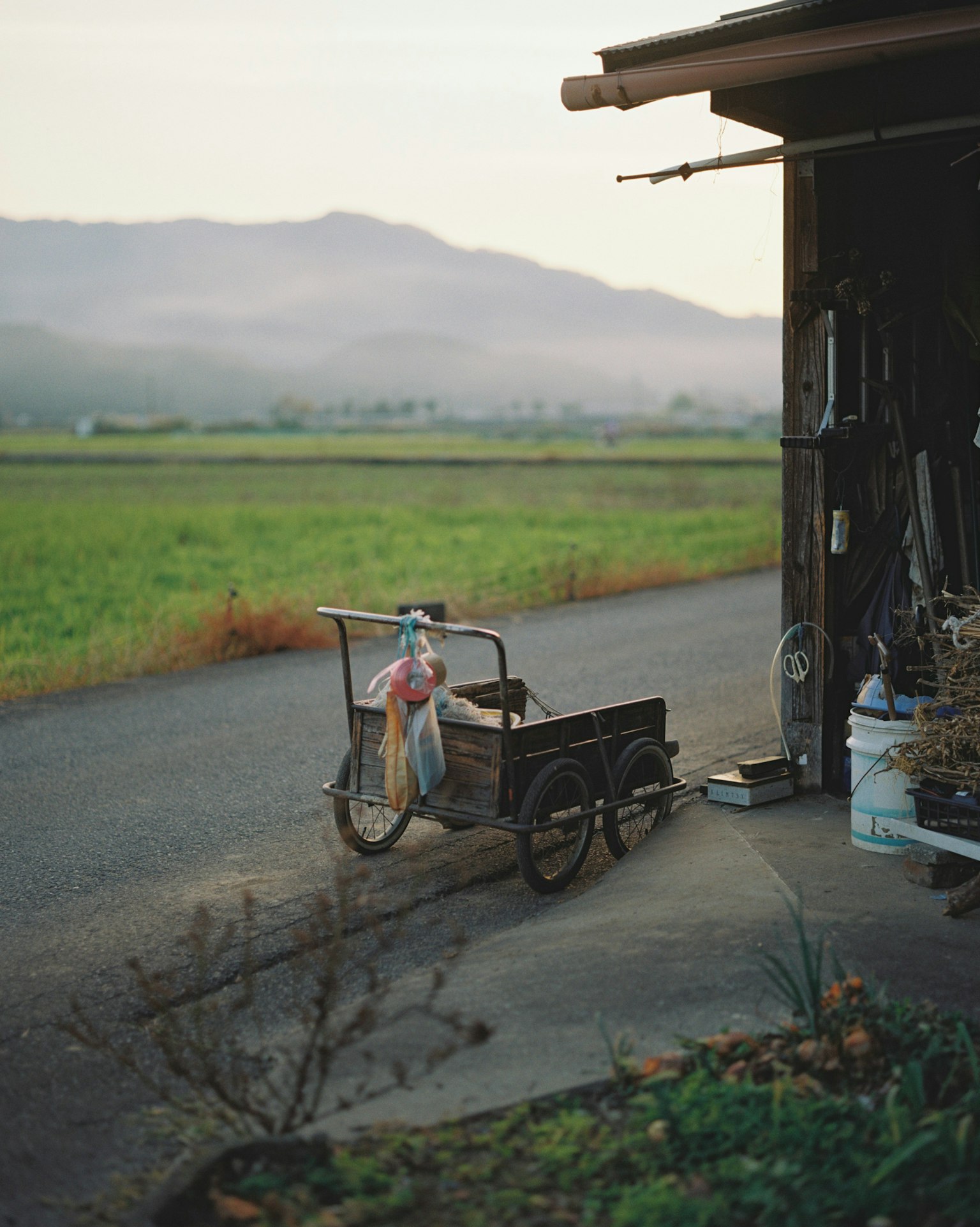 Vieux chariot à côté d'un abri dans un paysage rural avec des montagnes en arrière-plan