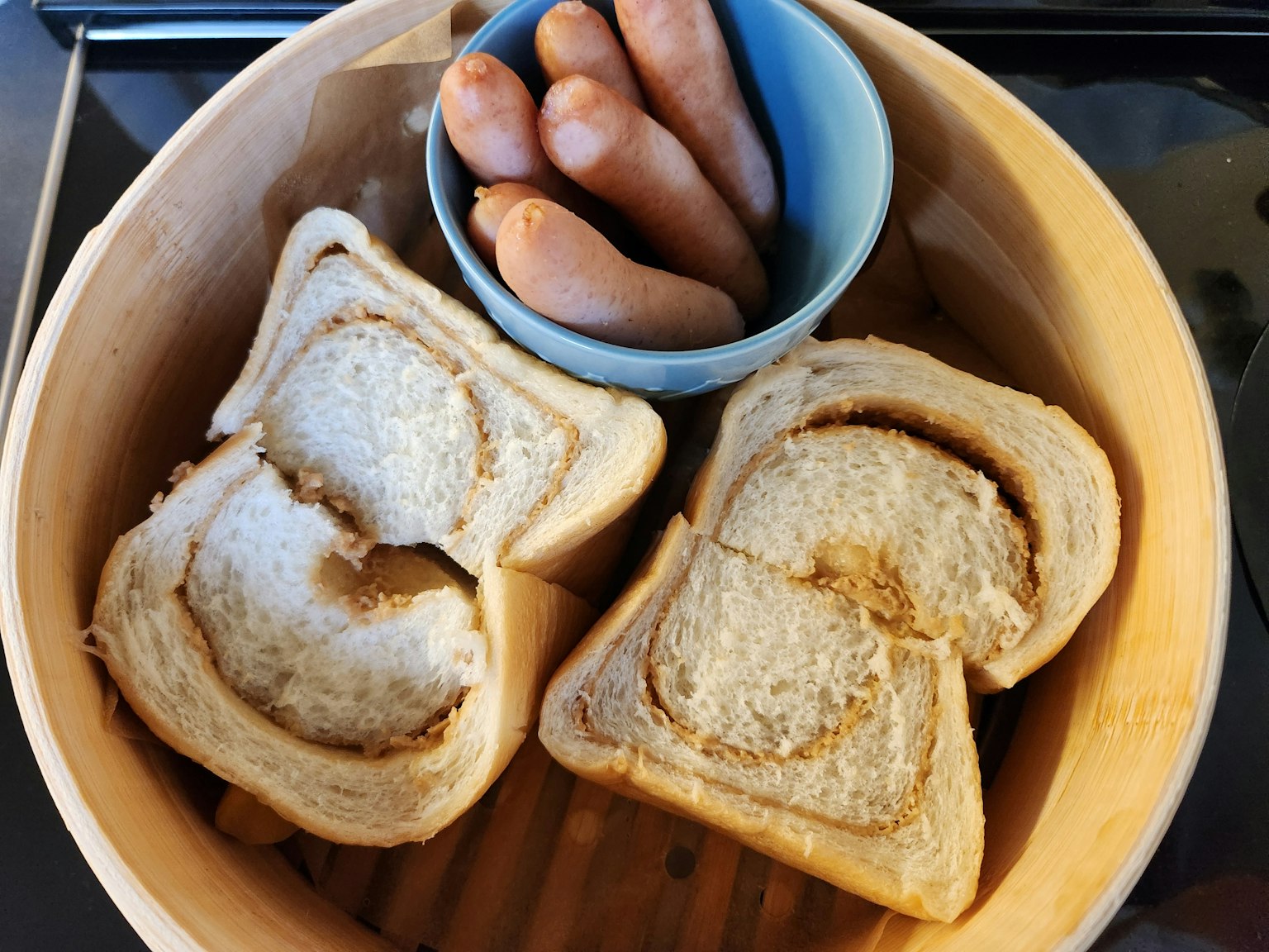 Roti iris dan mangkuk biru berisi sosis dalam pengukus