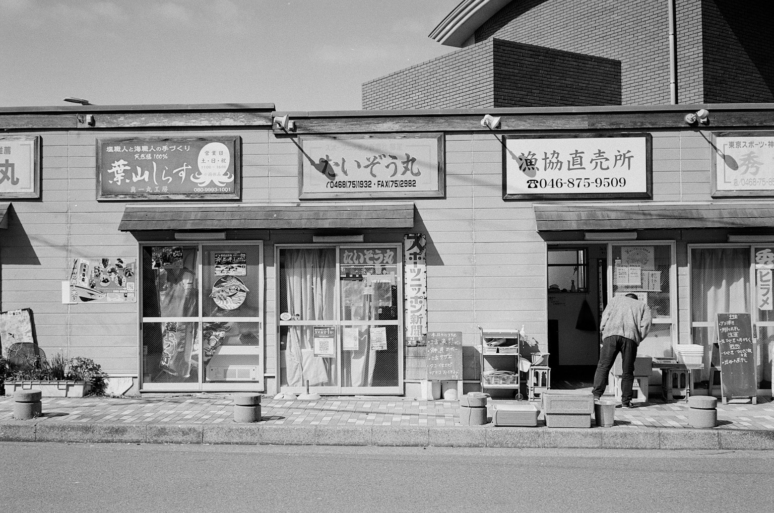 黑白街景，商店招牌和在外工作的商店主人