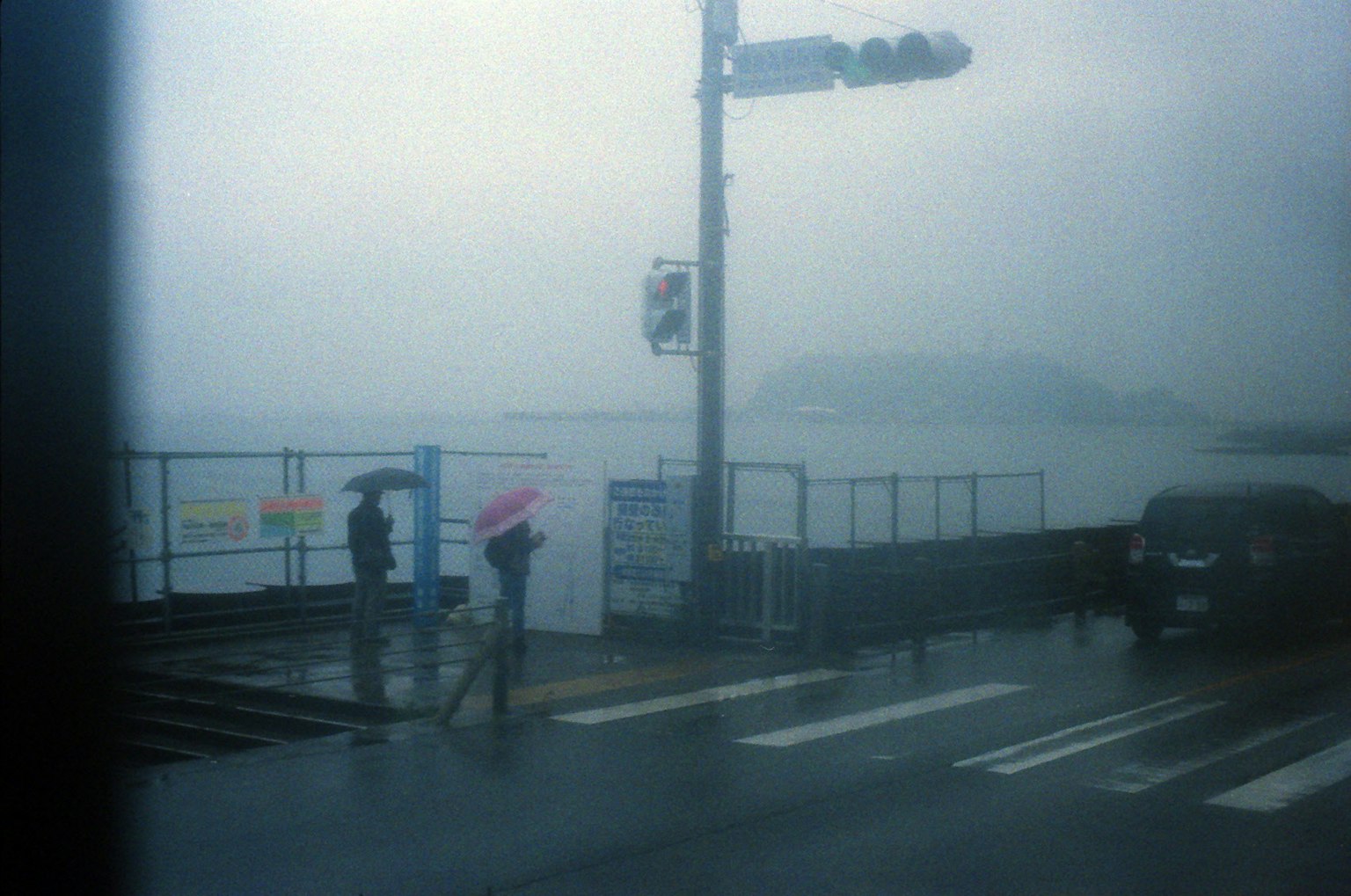 雨中人们在海边走路，撑着伞