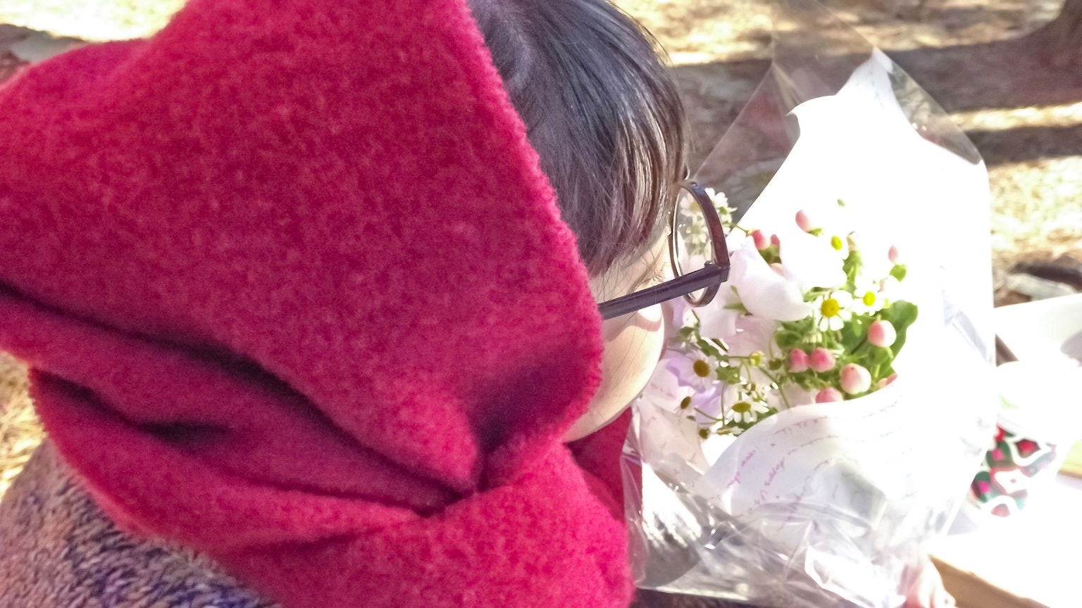 Mujer con bufanda roja sosteniendo un ramo de flores
