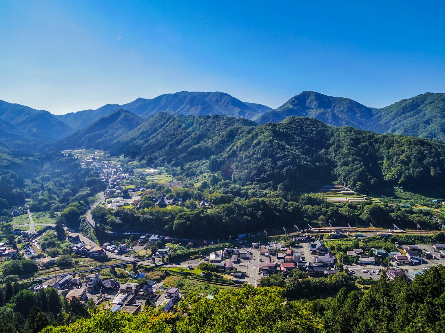 Paesaggio sereno del villaggio circondato da montagne e cielo blu