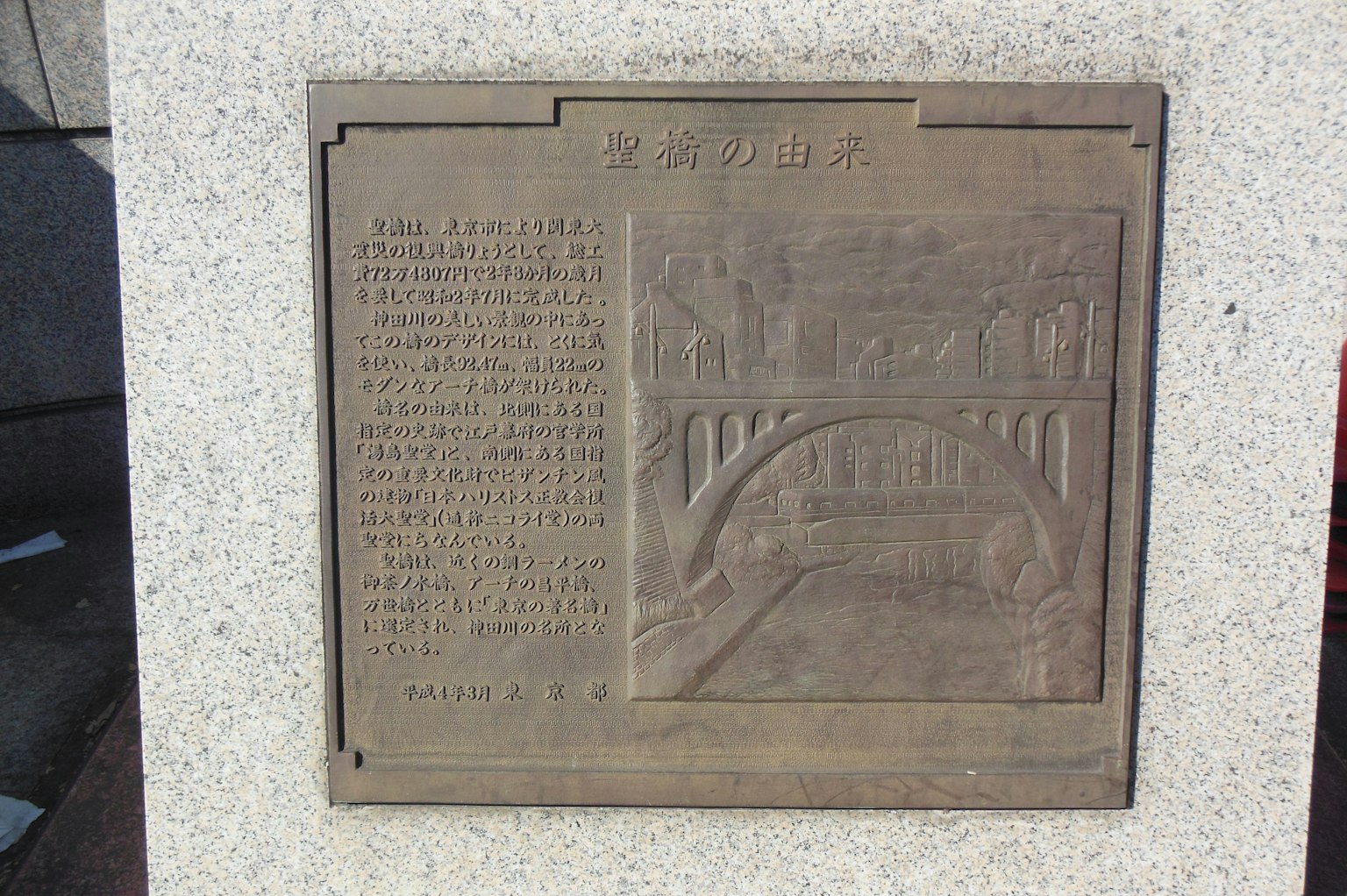 Placa de bronce que representa un puente con texto grabado