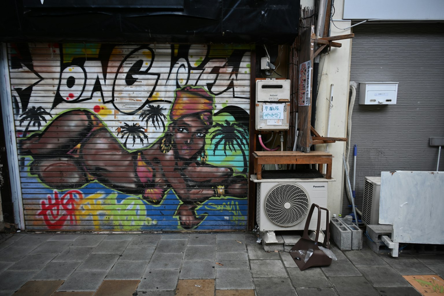 Bức tranh graffiti đầy màu sắc trên cửa cuốn với hình một con khỉ đội mũ và các yếu tố nhiệt đới