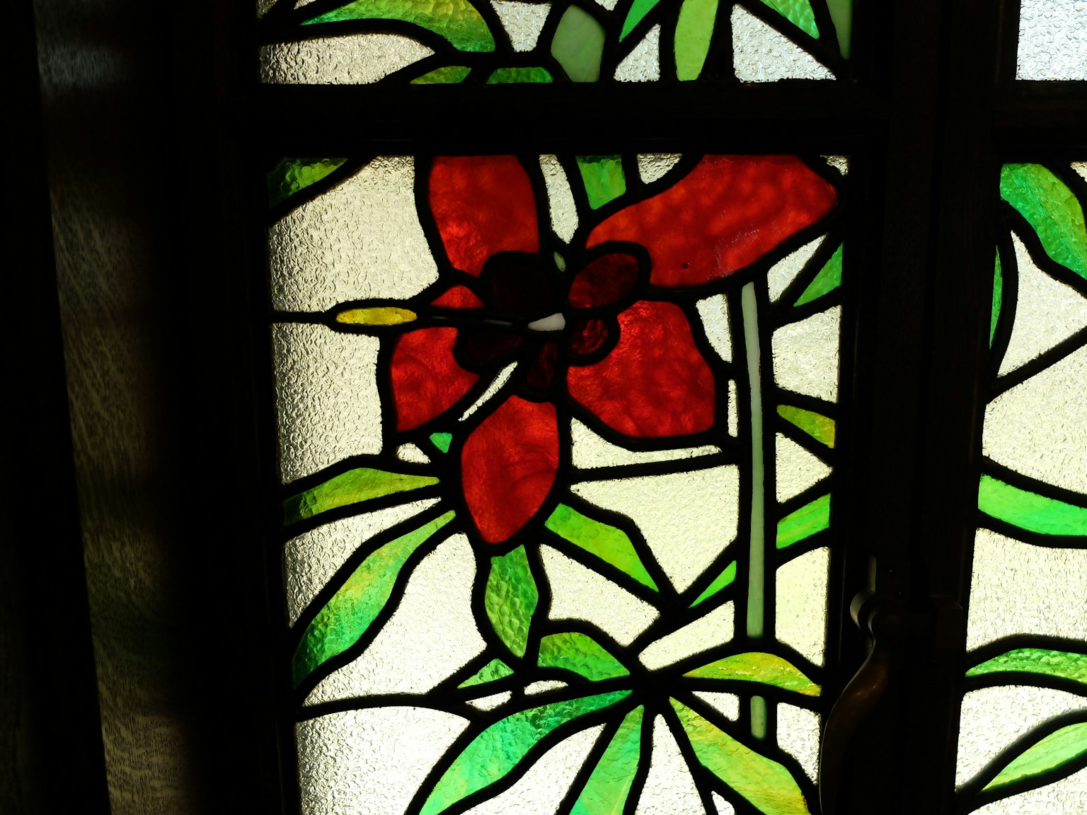 Design in vetro colorato con un fiore rosso e foglie verdi