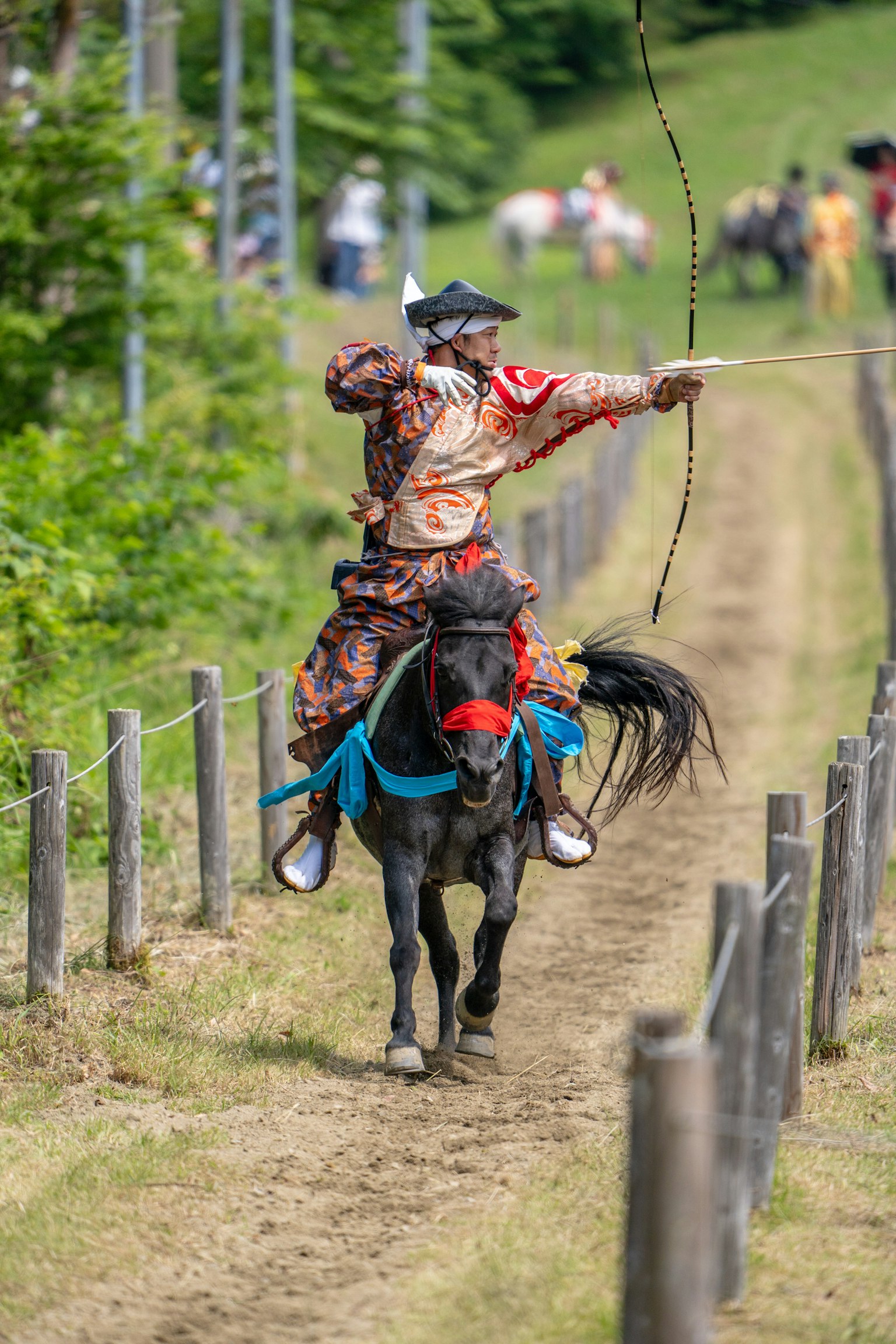 A warrior on horseback drawing a bow during a traditional festival