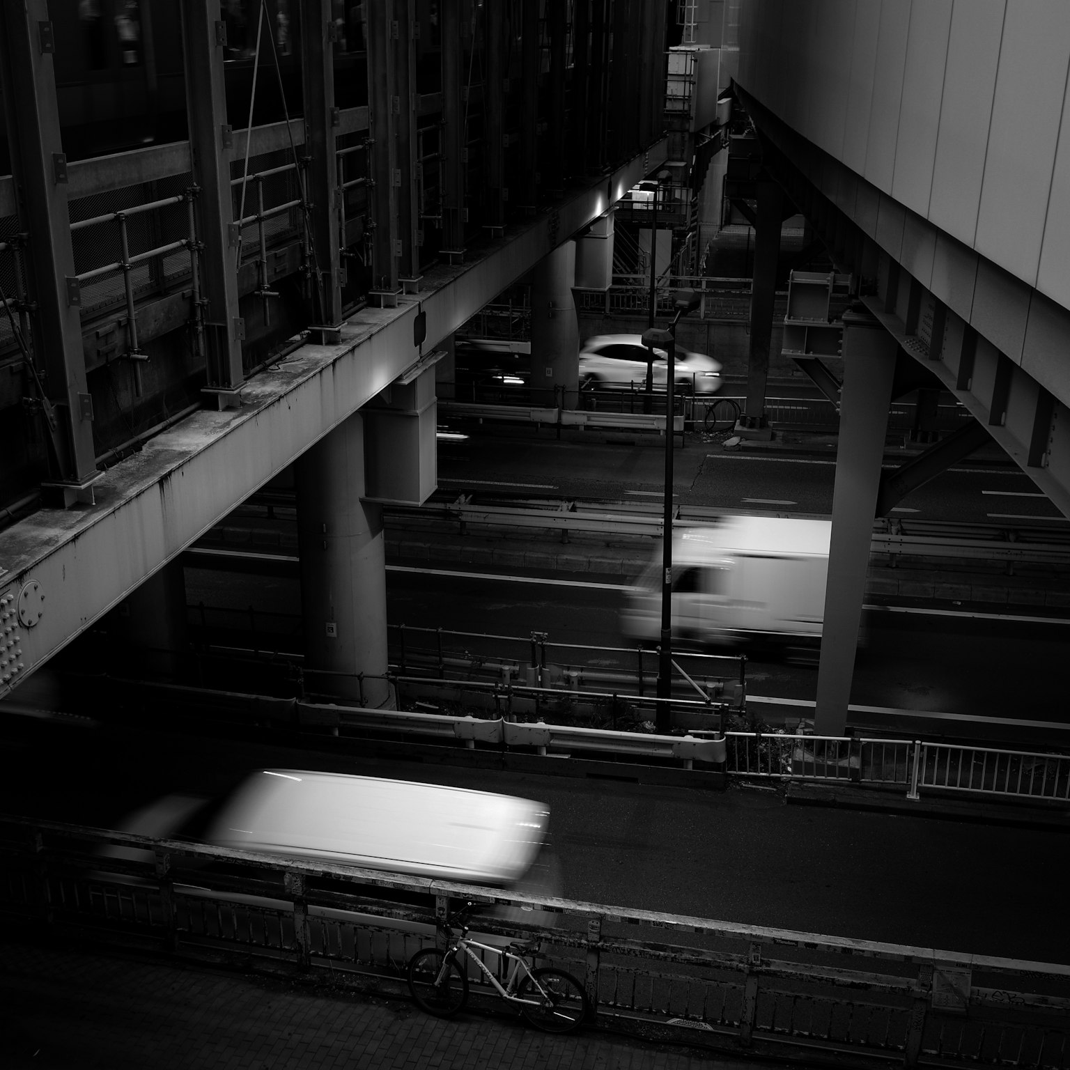 モノクロの都市風景 車両が高速道路を走る 構造物の柱が視界に入る