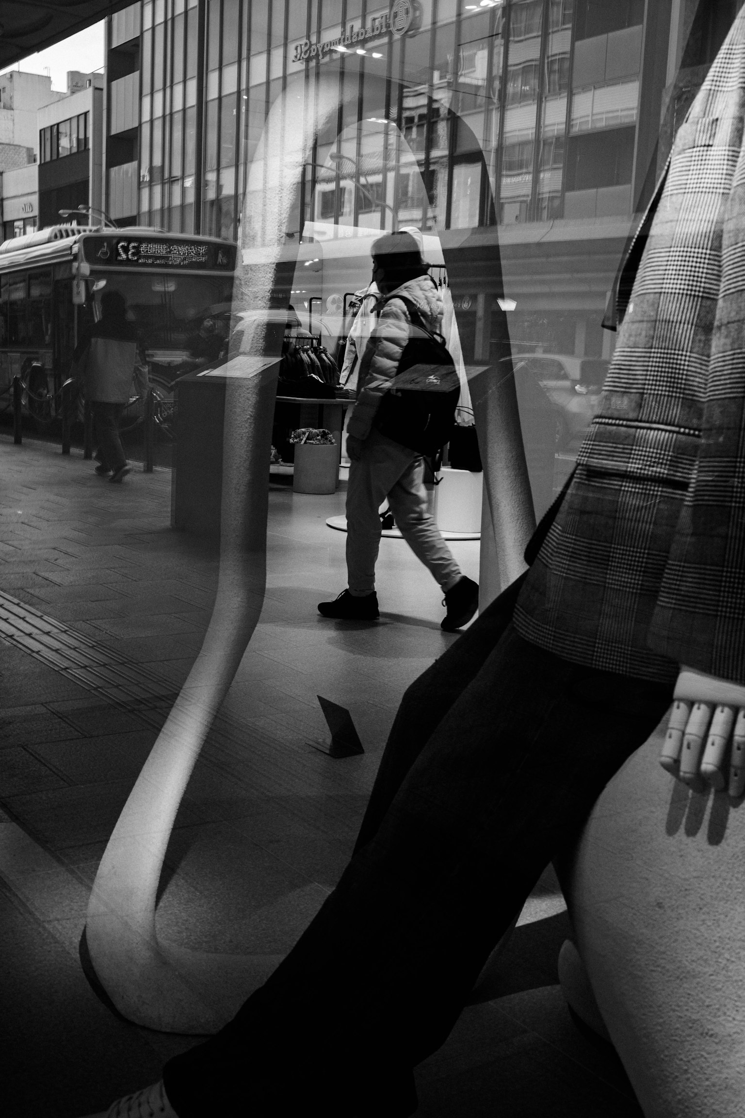 Escena callejera en blanco y negro que refleja a una persona y un maniquí en contraste