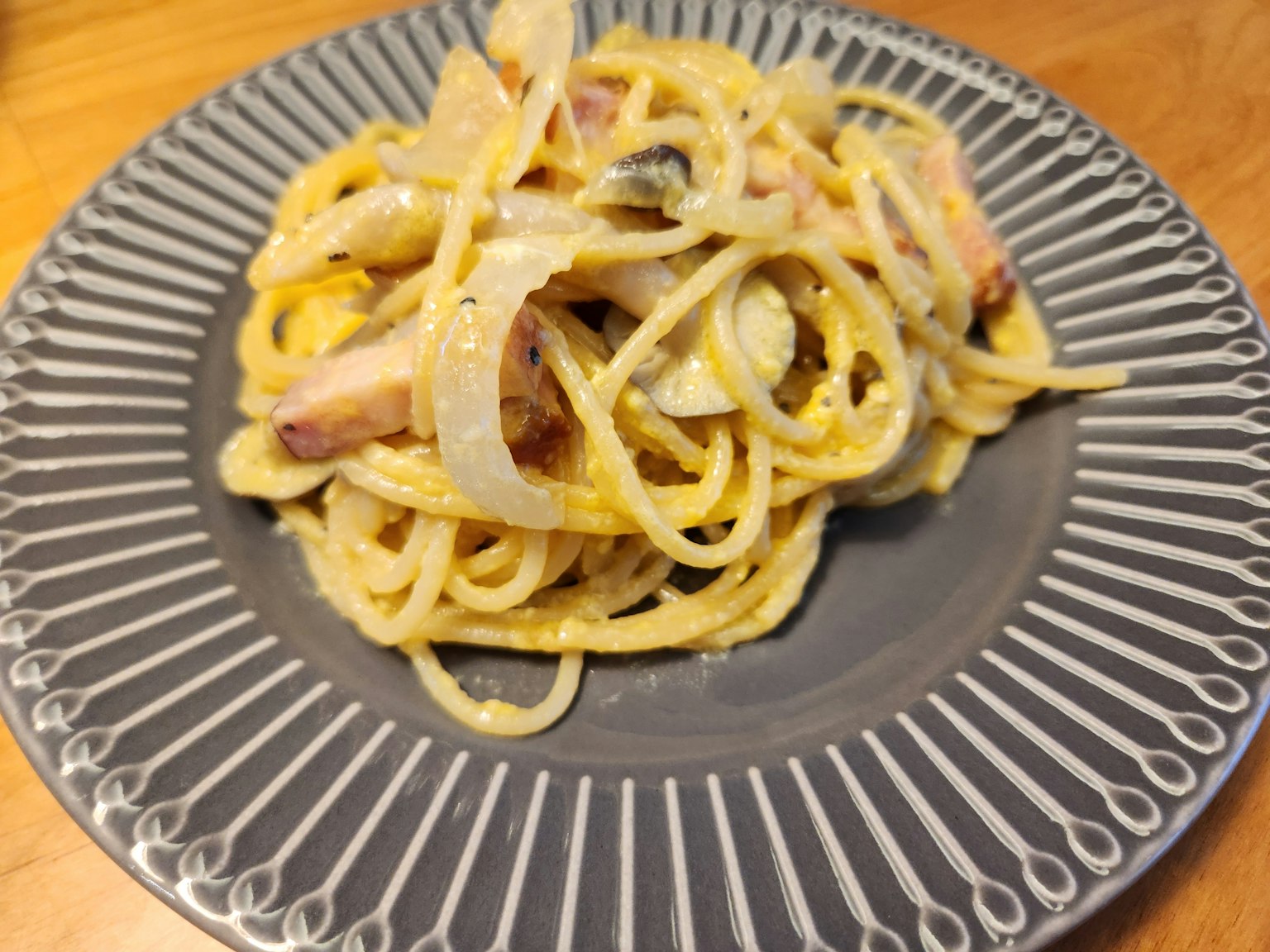 Hidangan pasta krim disajikan di atas piring dekoratif dengan bawang