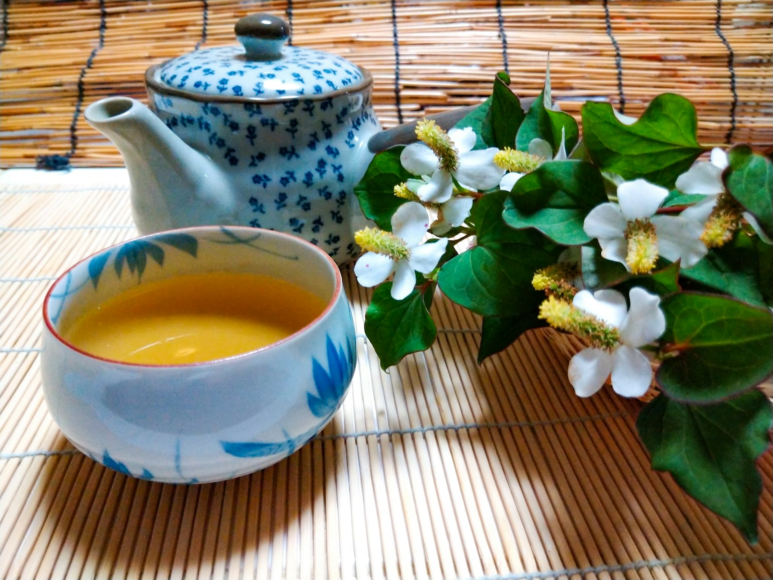 藍色花紋茶壺，盛有黃色茶的碗和白色花束