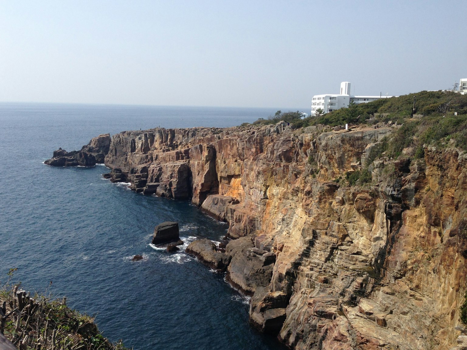 Landschaft mit felsigen Klippen am Meer und einem nahegelegenen Gebäude