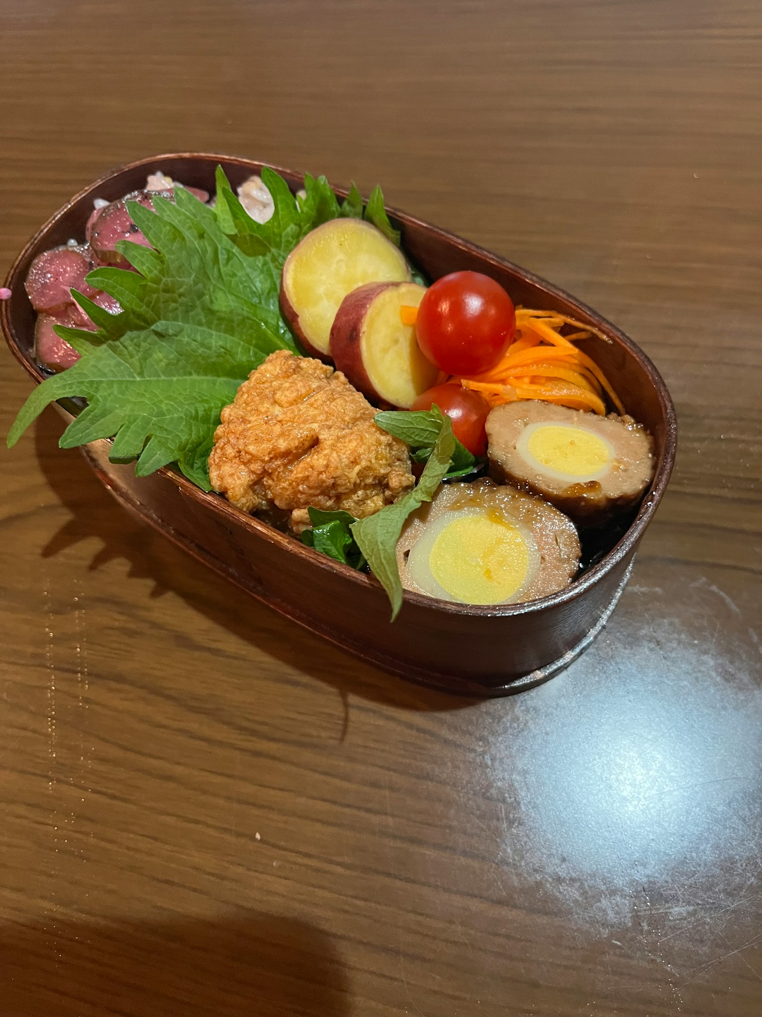 Una caja bento con una croqueta crujiente y verduras coloridas
