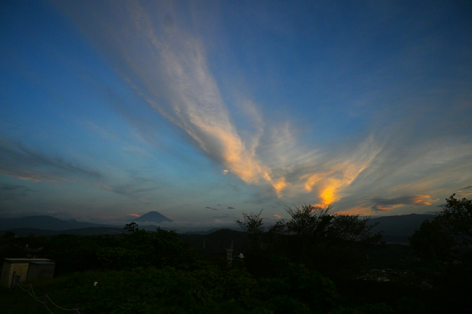 Cielo de atardecer colorido con nubes delgadas y montañas a lo lejos