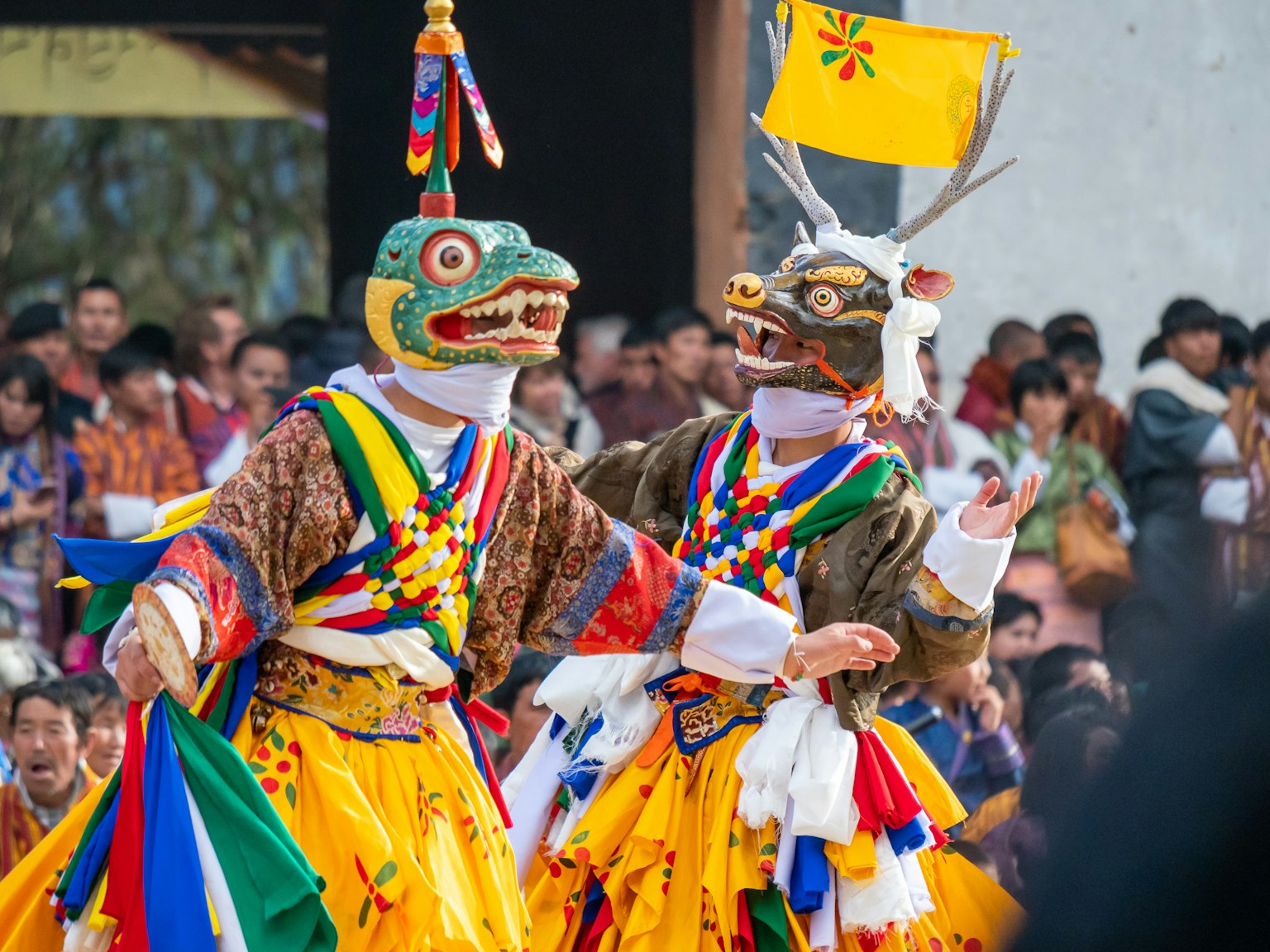 Due danzatori in costumi tradizionali che indossano maschere colorate mentre danzano