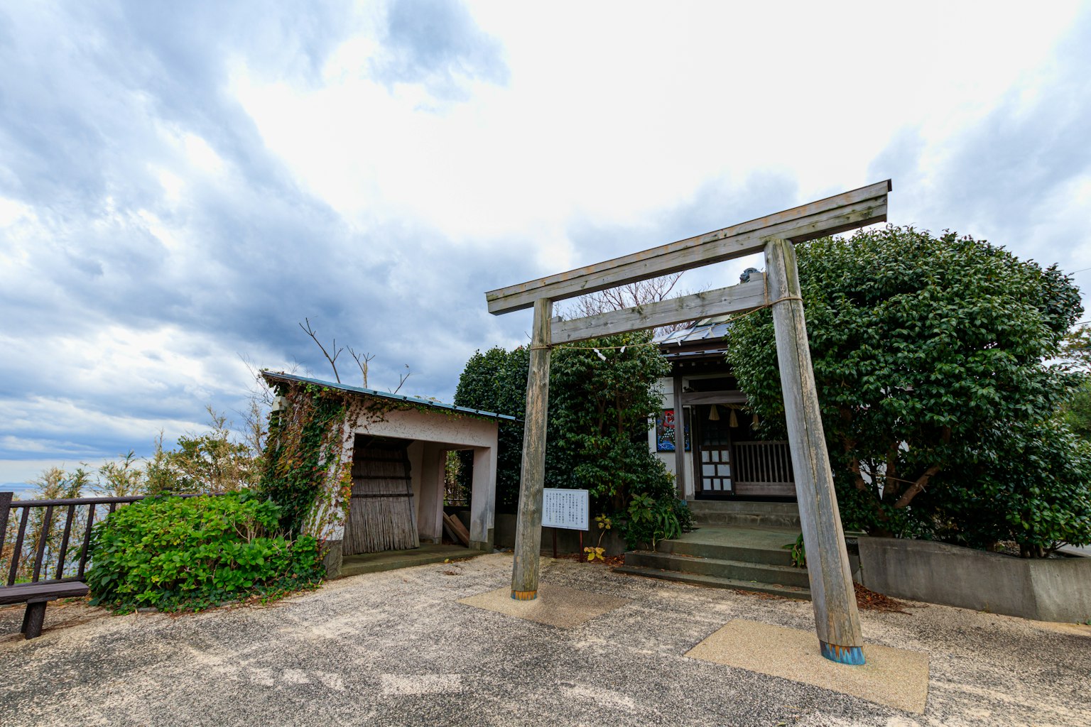 Un torii con vegetazione e cielo nuvoloso