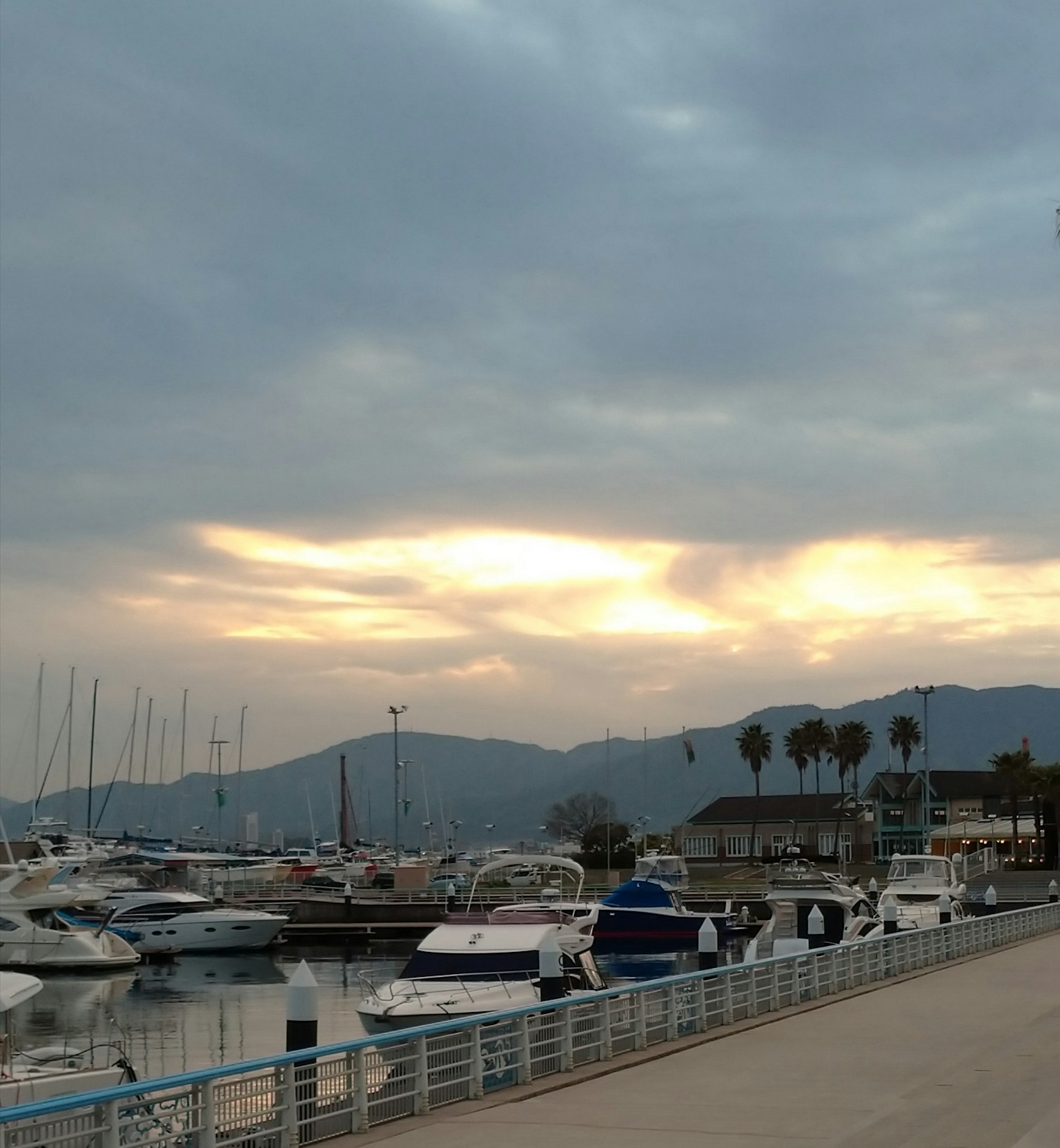 Vue du coucher de soleil sur un port avec des bateaux et des montagnes en arrière-plan