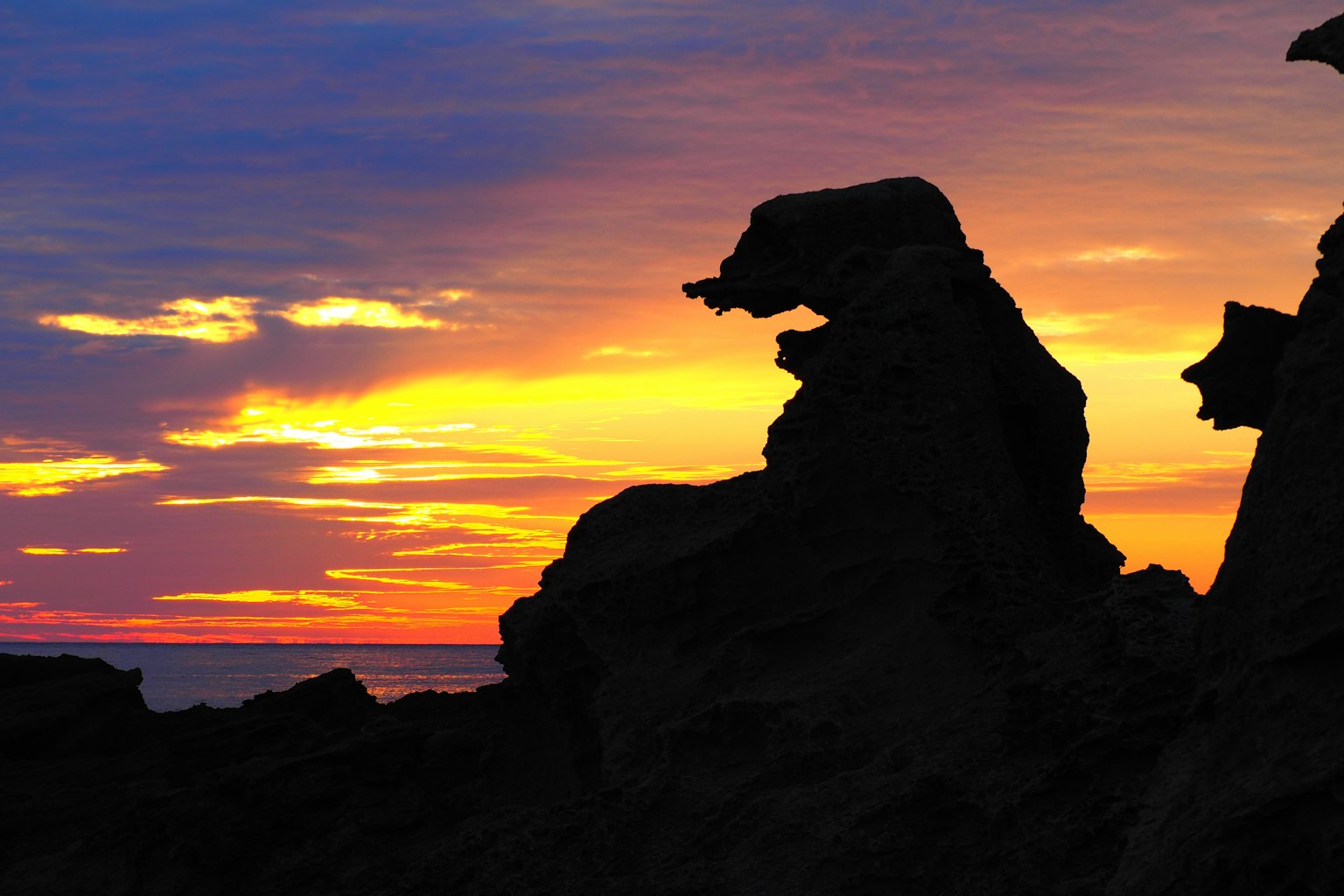 Silhouette von Felsen vor einem lebhaften Sonnenuntergangshimmel