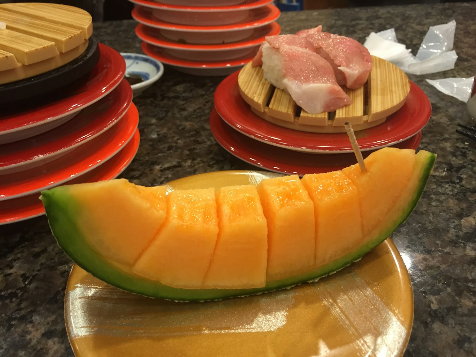 Rebanada de melón deliciosa en un plato con sushi al fondo