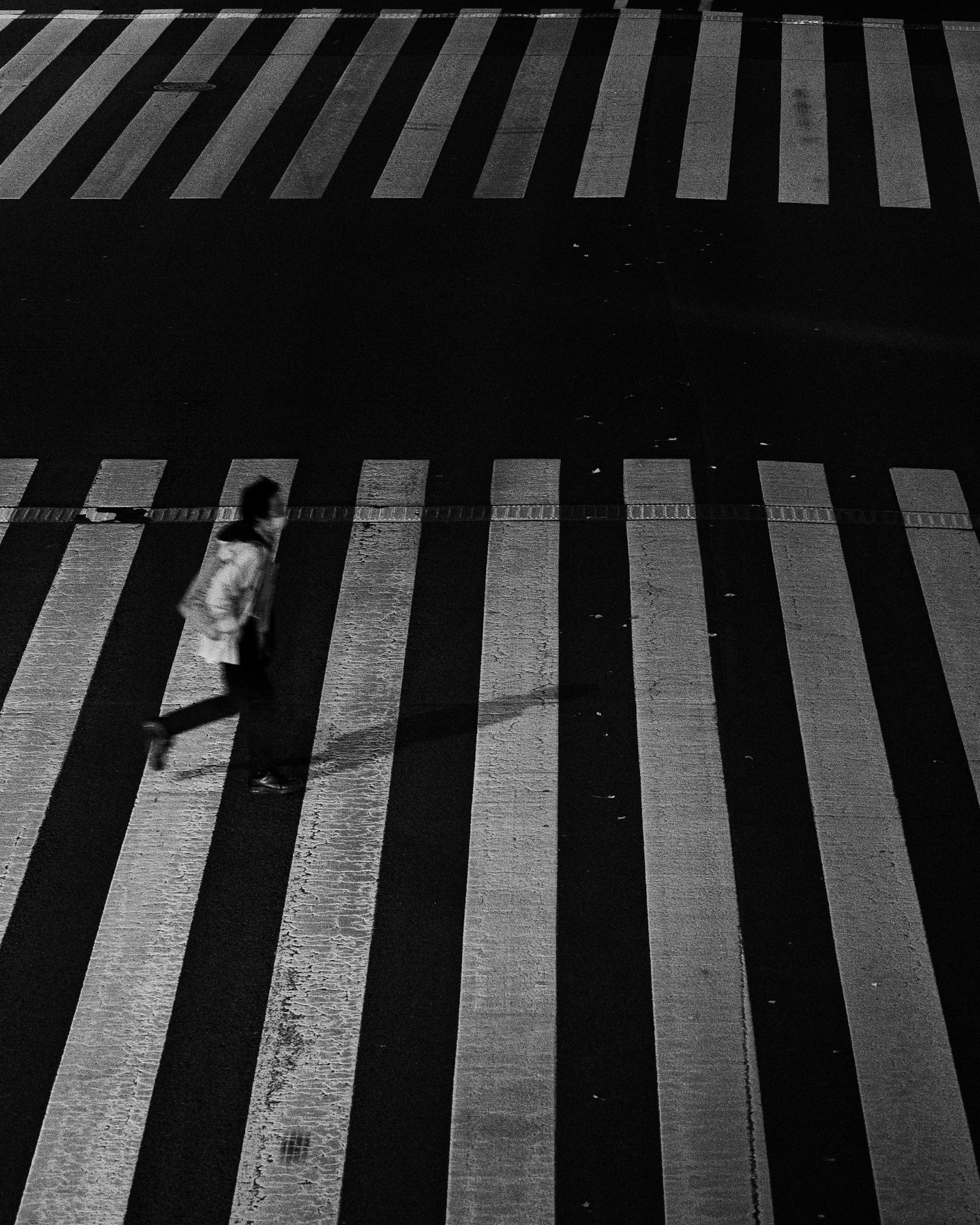 Una persona caminando en un paso de peatones blanco y negro