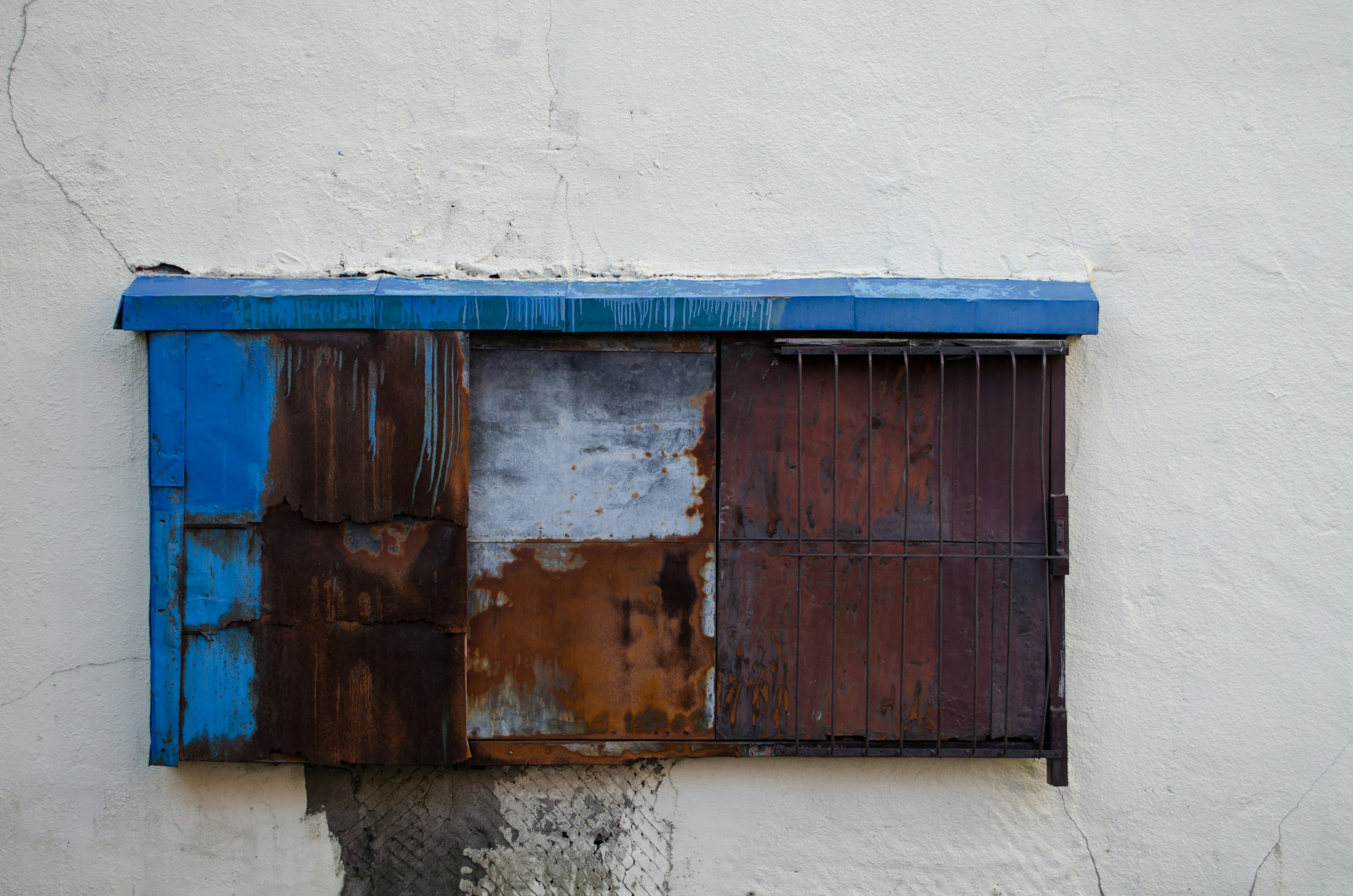 muro con pensilina blu e saracinesca metallica arrugginita