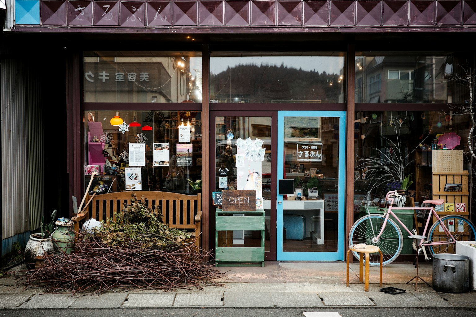 Vitrine d'un petit magasin avec des décorations colorées incluant un banc en bois et un vélo