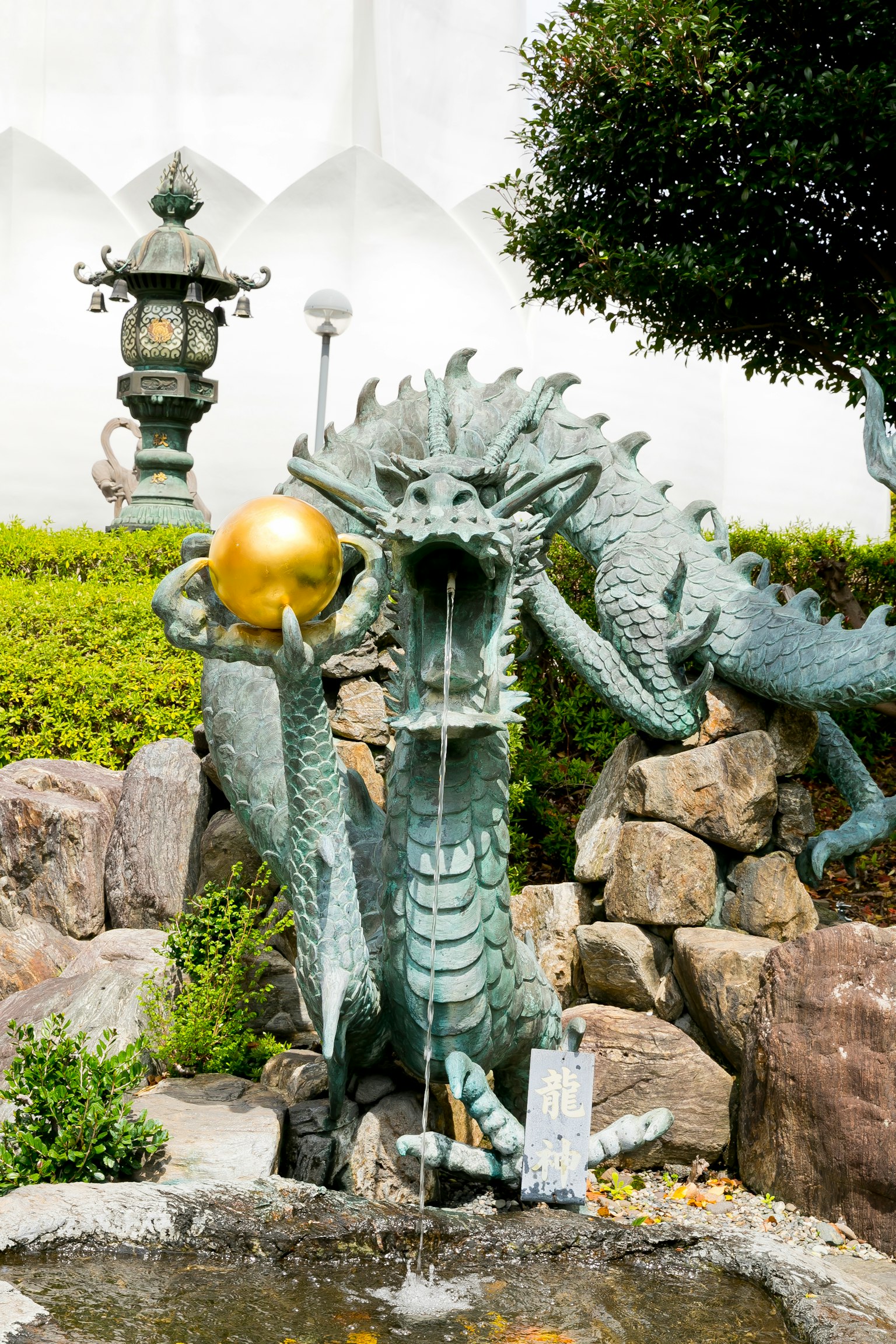 Drachenbrunnen mit einer goldenen Kugel in einem schönen Garten