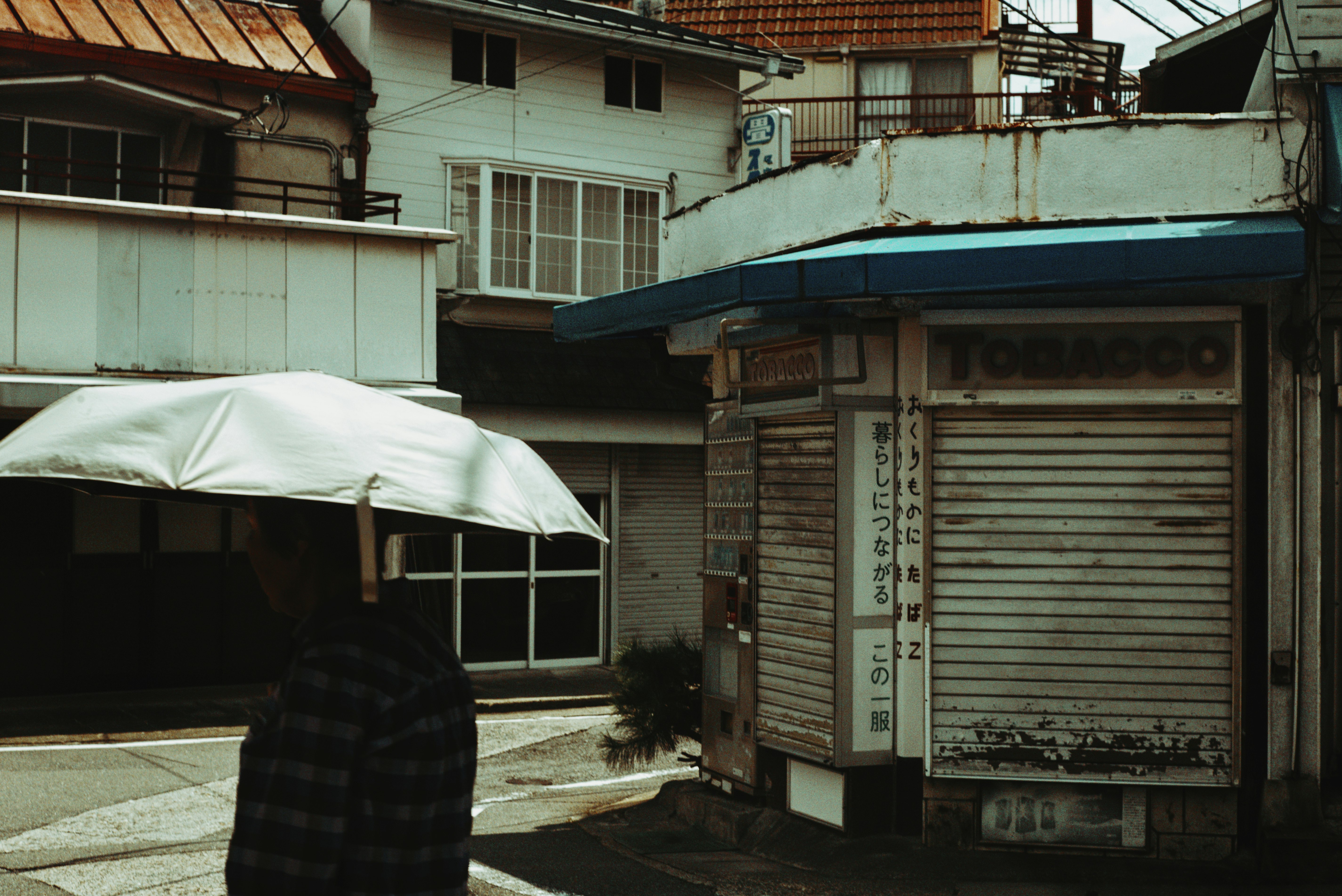 Kyoto alley storefront with a closed shutter and an umbrella