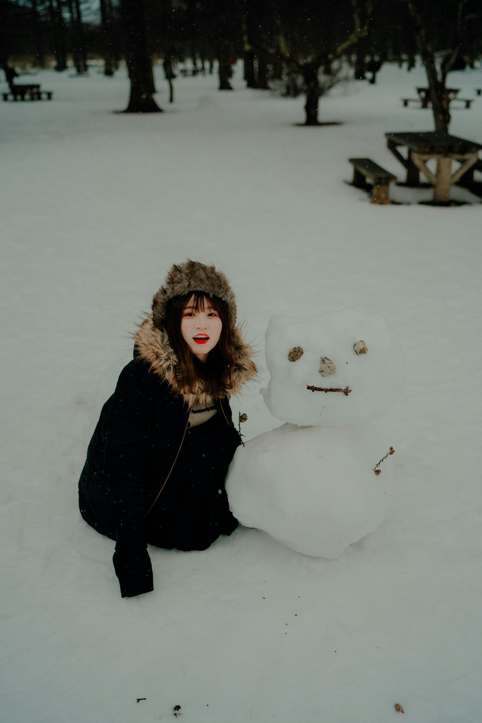 Eine Frau spielt mit einem Schneemann im Schnee