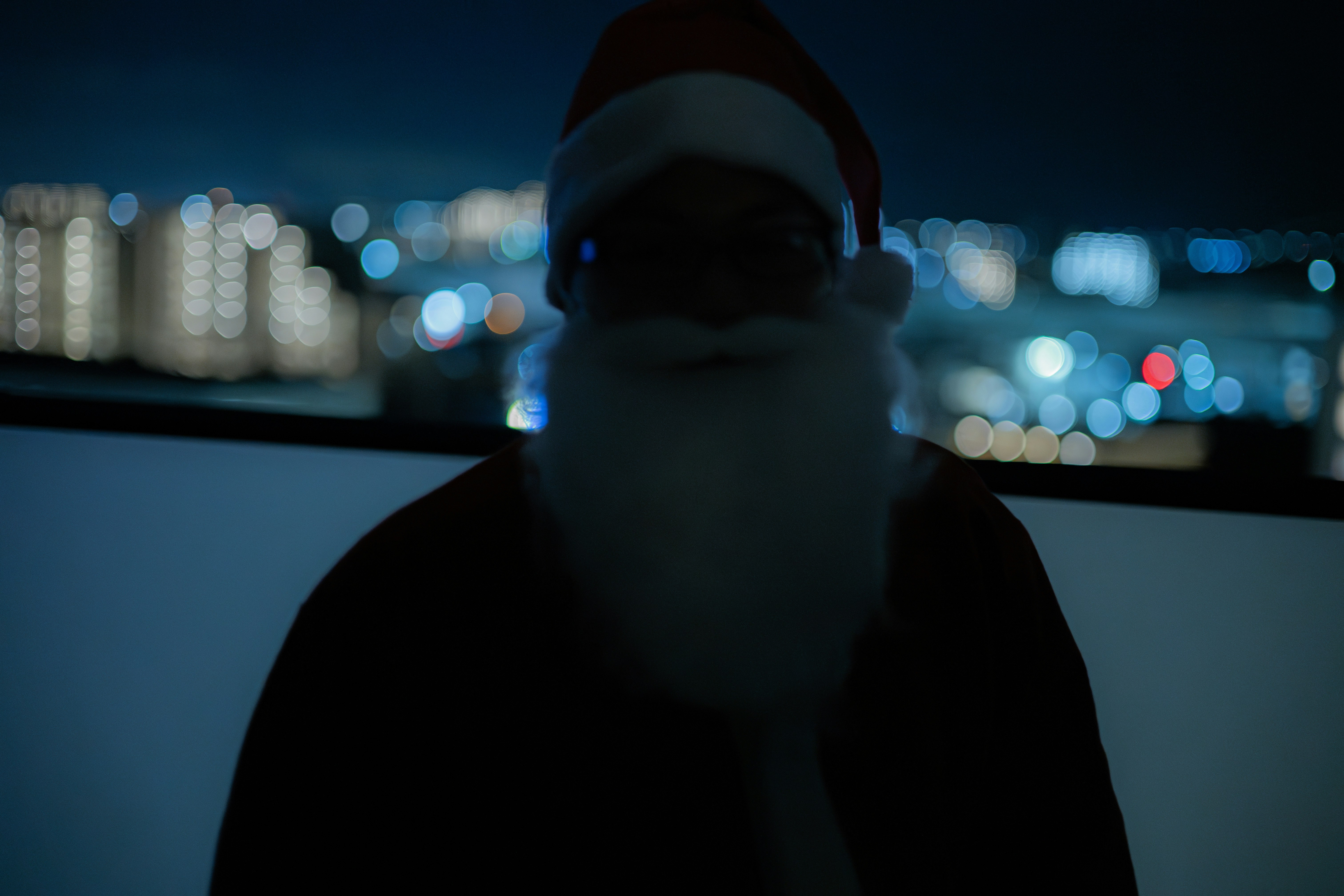 夜の街並みを背景にしたフード付き人物のシルエット