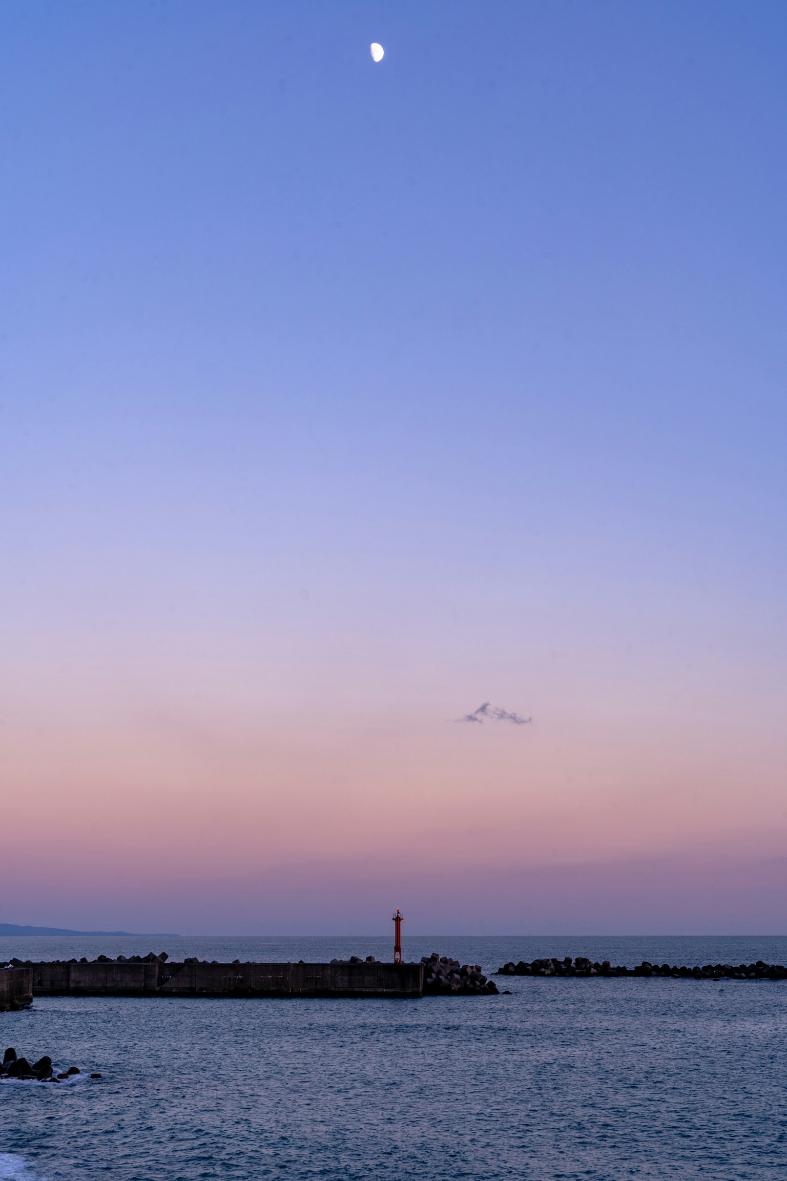 黄昏天空中的月亮和灯塔的轮廓