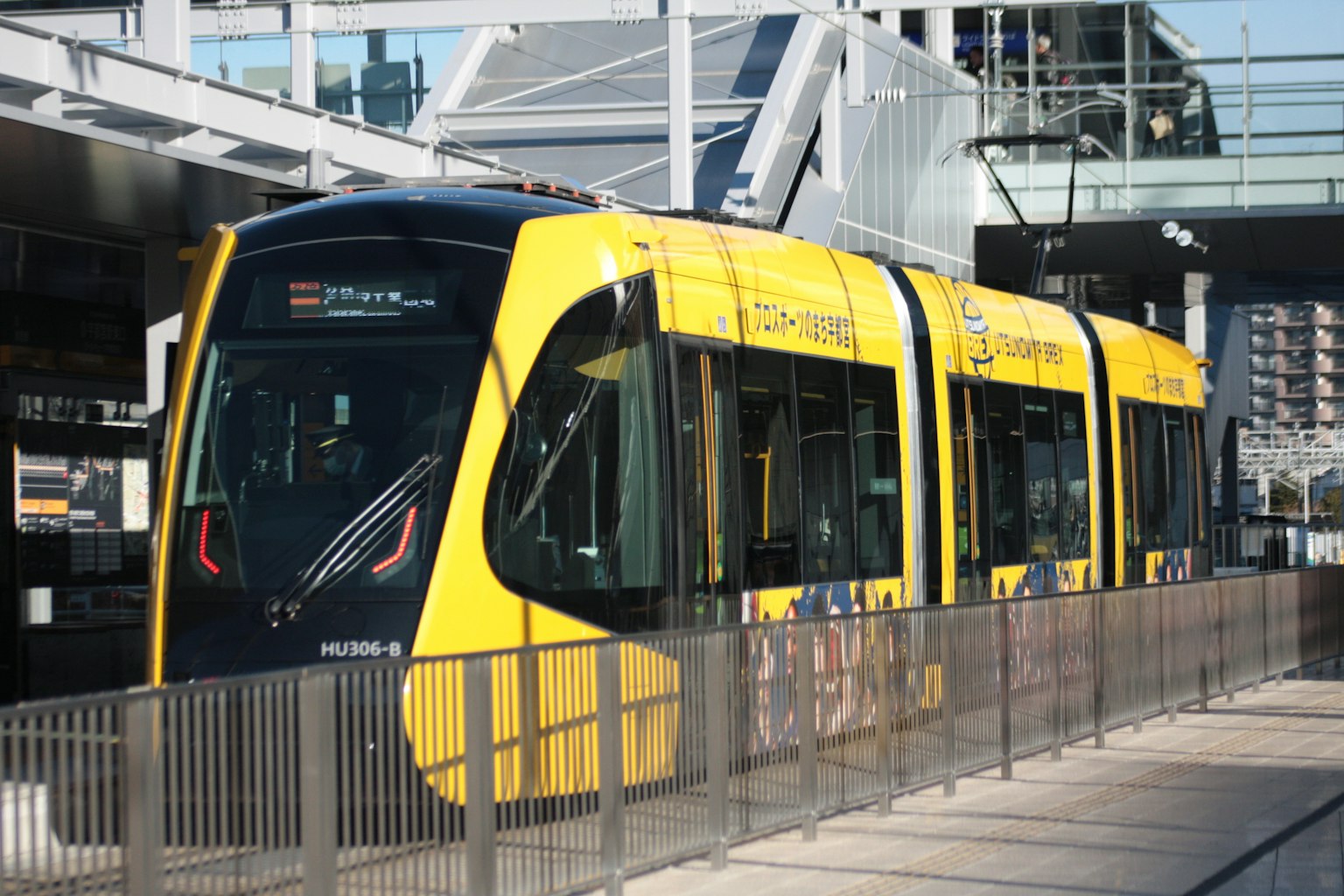 Trem kuning terparkir di stasiun dengan arsitektur modern