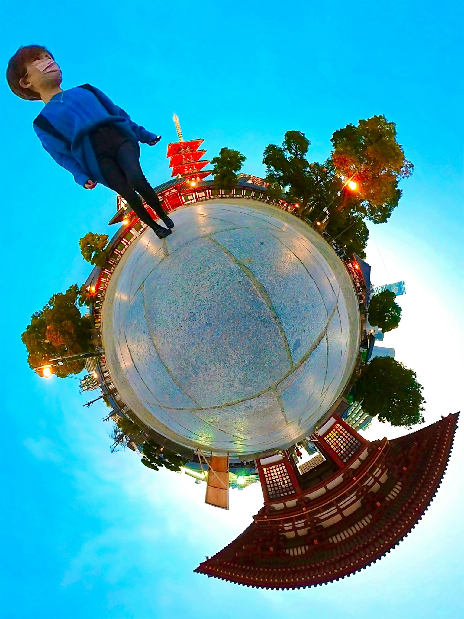 Boy walking under a blue sky surrounded by trees and buildings showcasing a unique perspective