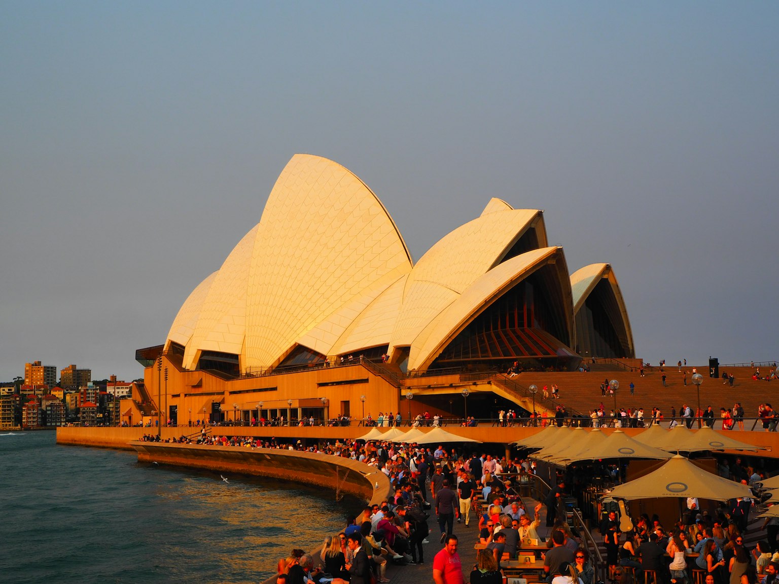 Sydney Opera House dengan arsitektur unik dan kerumunan saat matahari terbenam