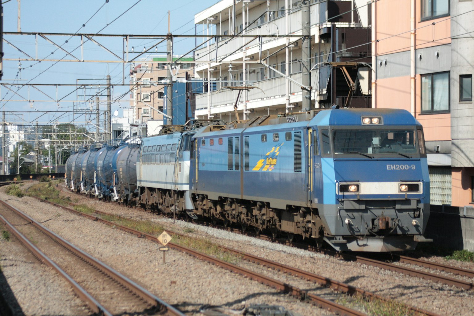 Blauer Güterzug, der auf Gleisen in städtischer Umgebung fährt