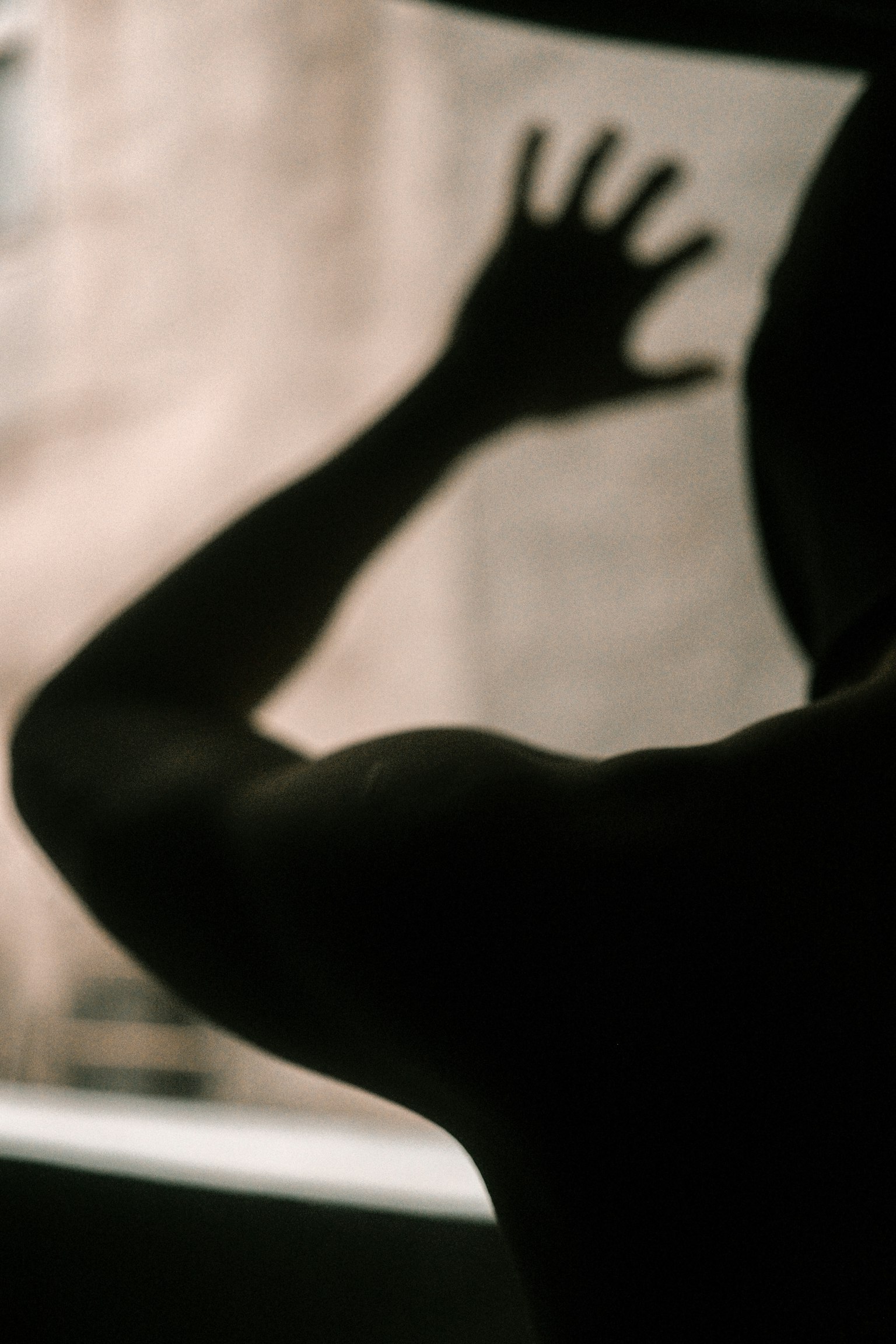 影の中で手を伸ばす人のシルエット 背景はぼやけた建物
