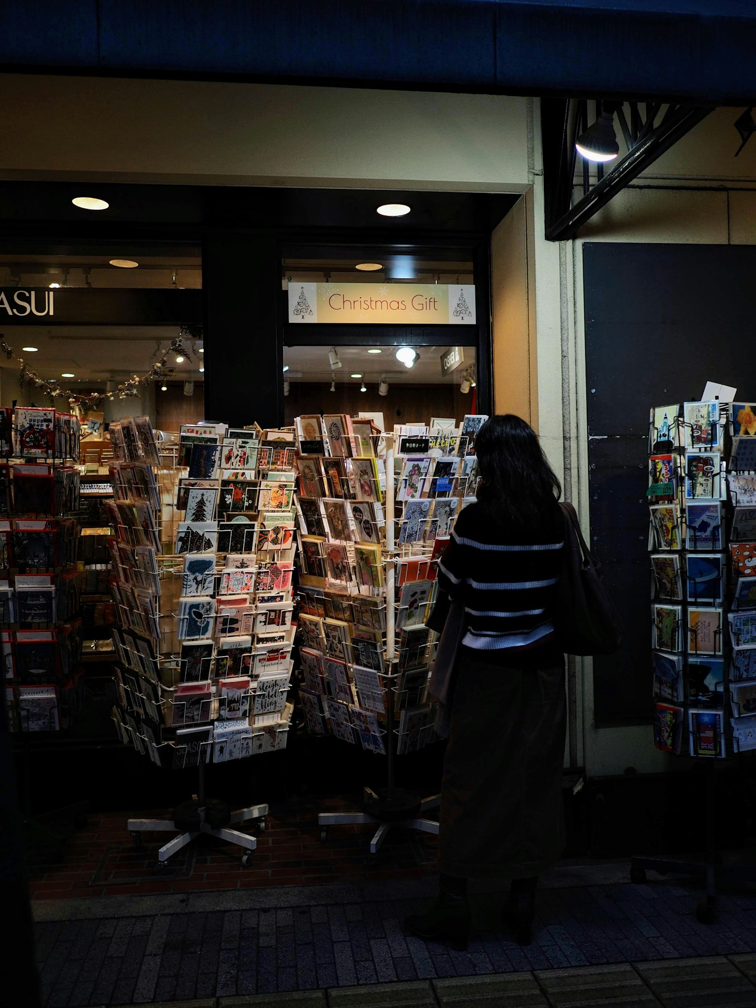 Femme se tenant devant des présentoirs de magazines à l'extérieur d'un magasin