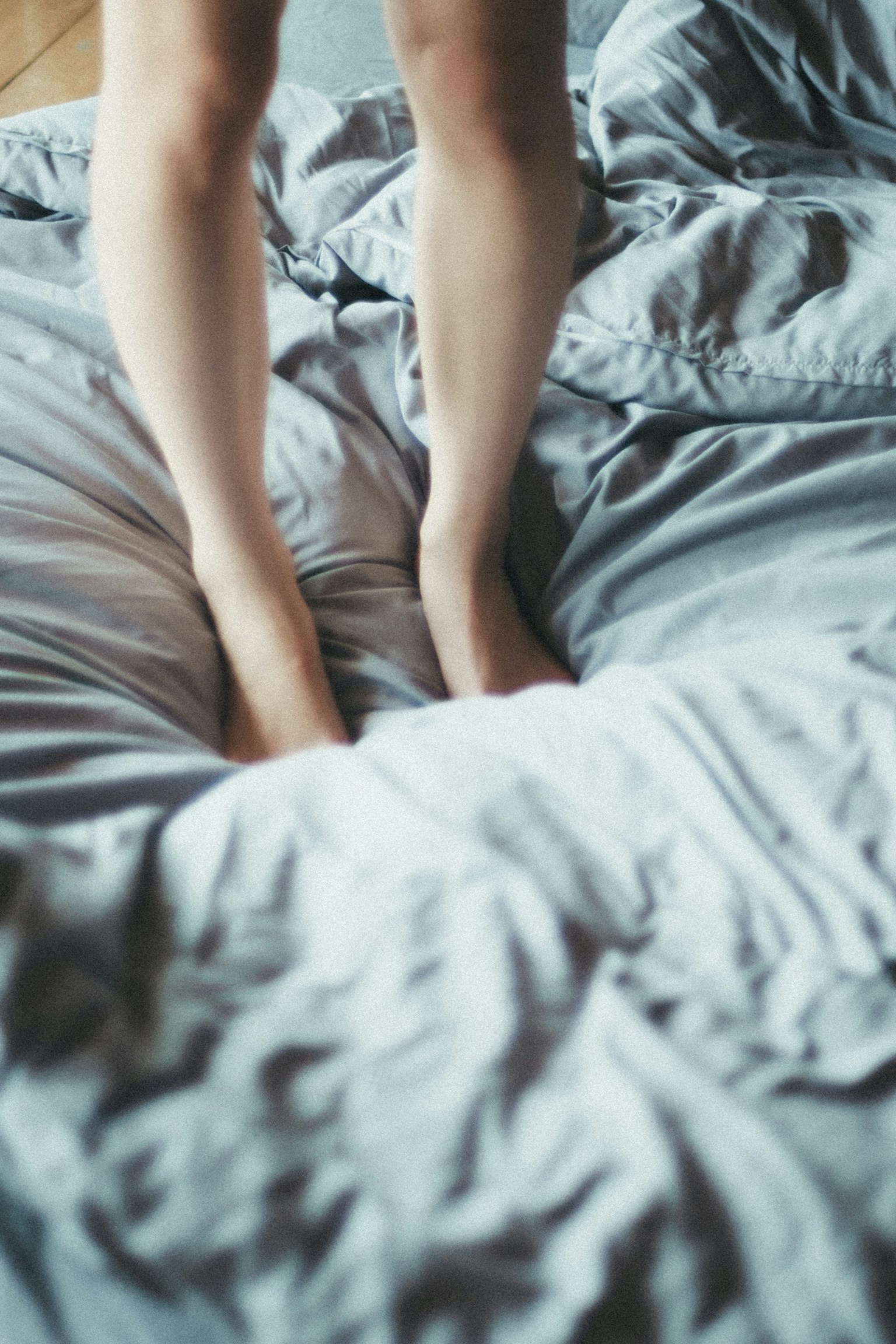 Chân trần của một người đứng trên ga trải giường nhăn