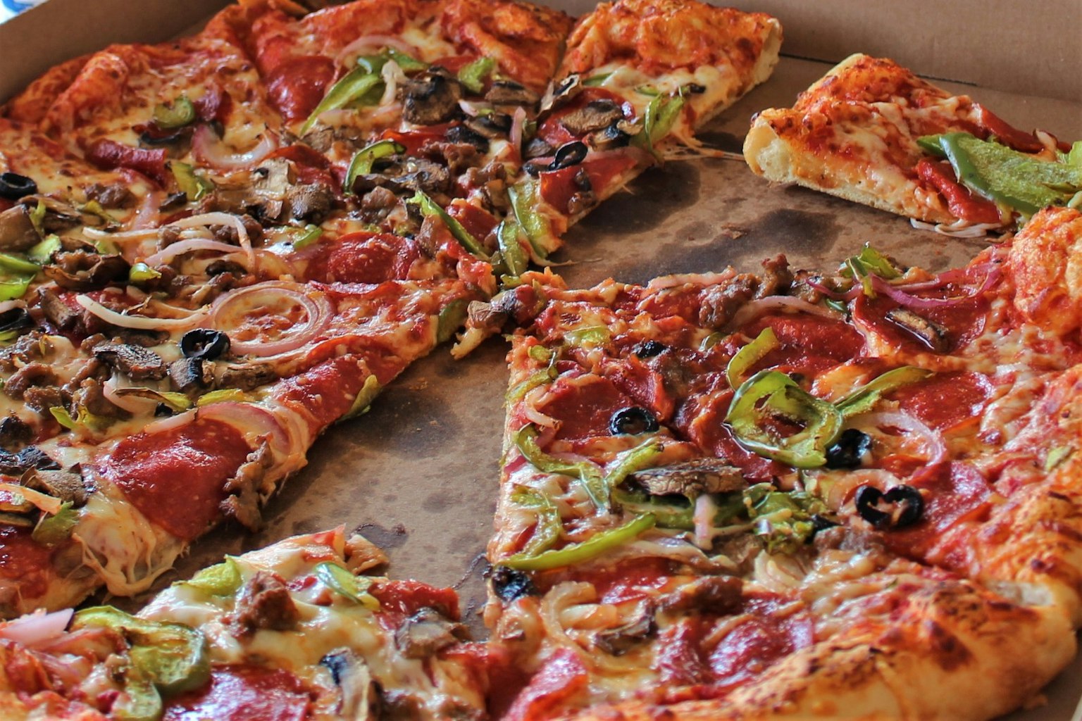 Pizza slices topped with pepperoni, olives, green peppers, and mushrooms