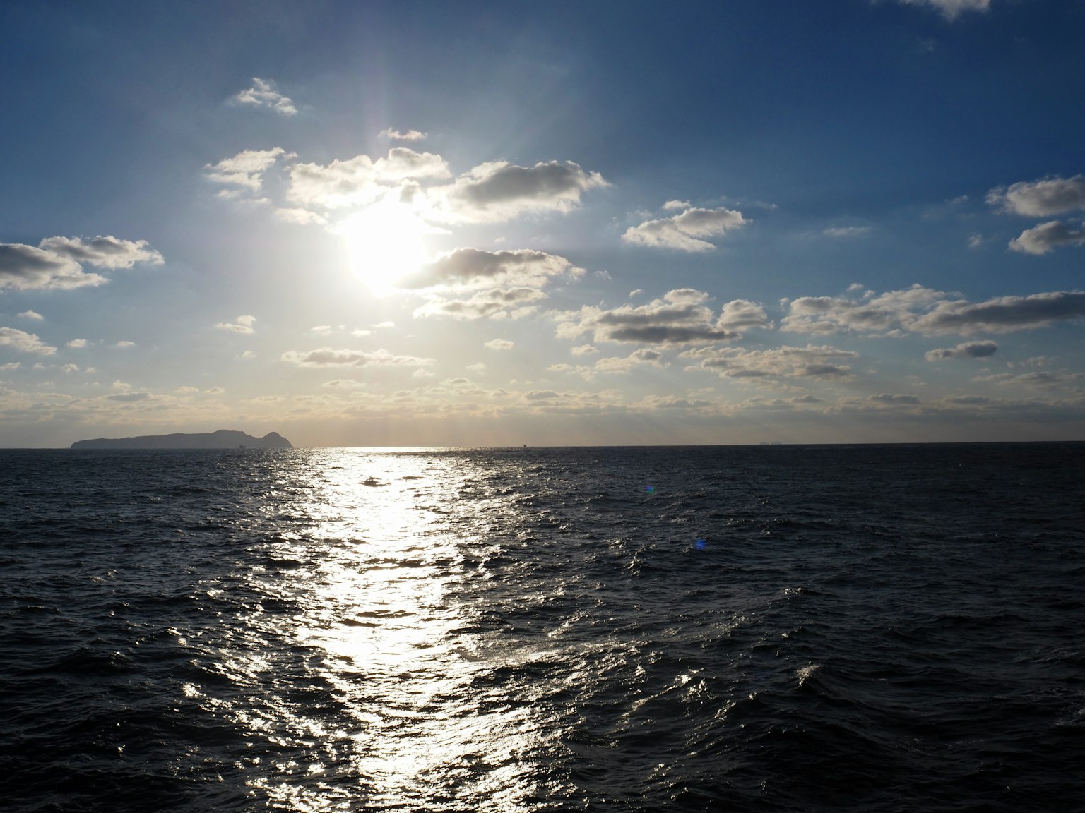 Sole splendente sopra l'oceano con nuvole in un cielo blu