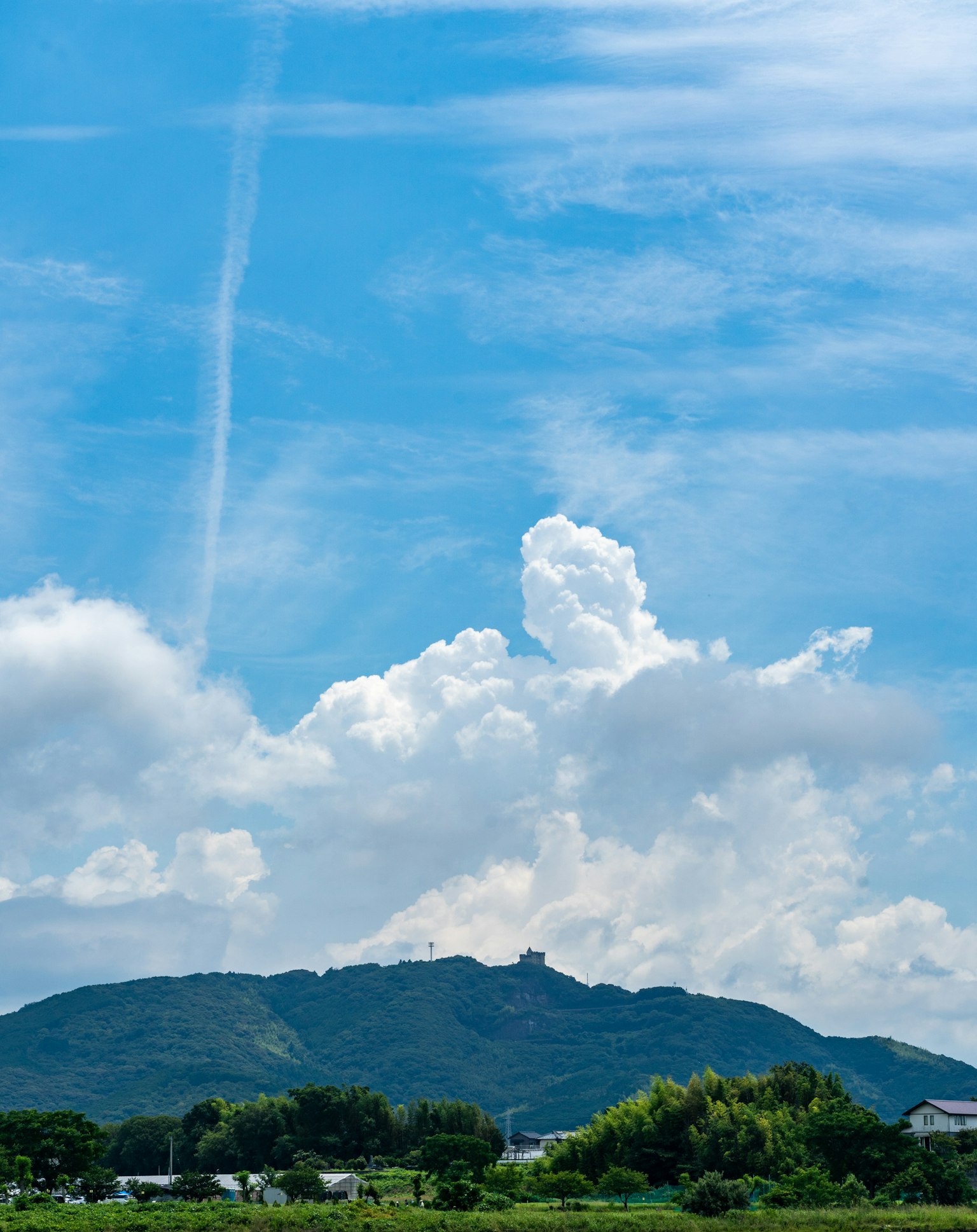 Vista panoramica di un cielo blu con nuvole bianche soffici e montagne verdi