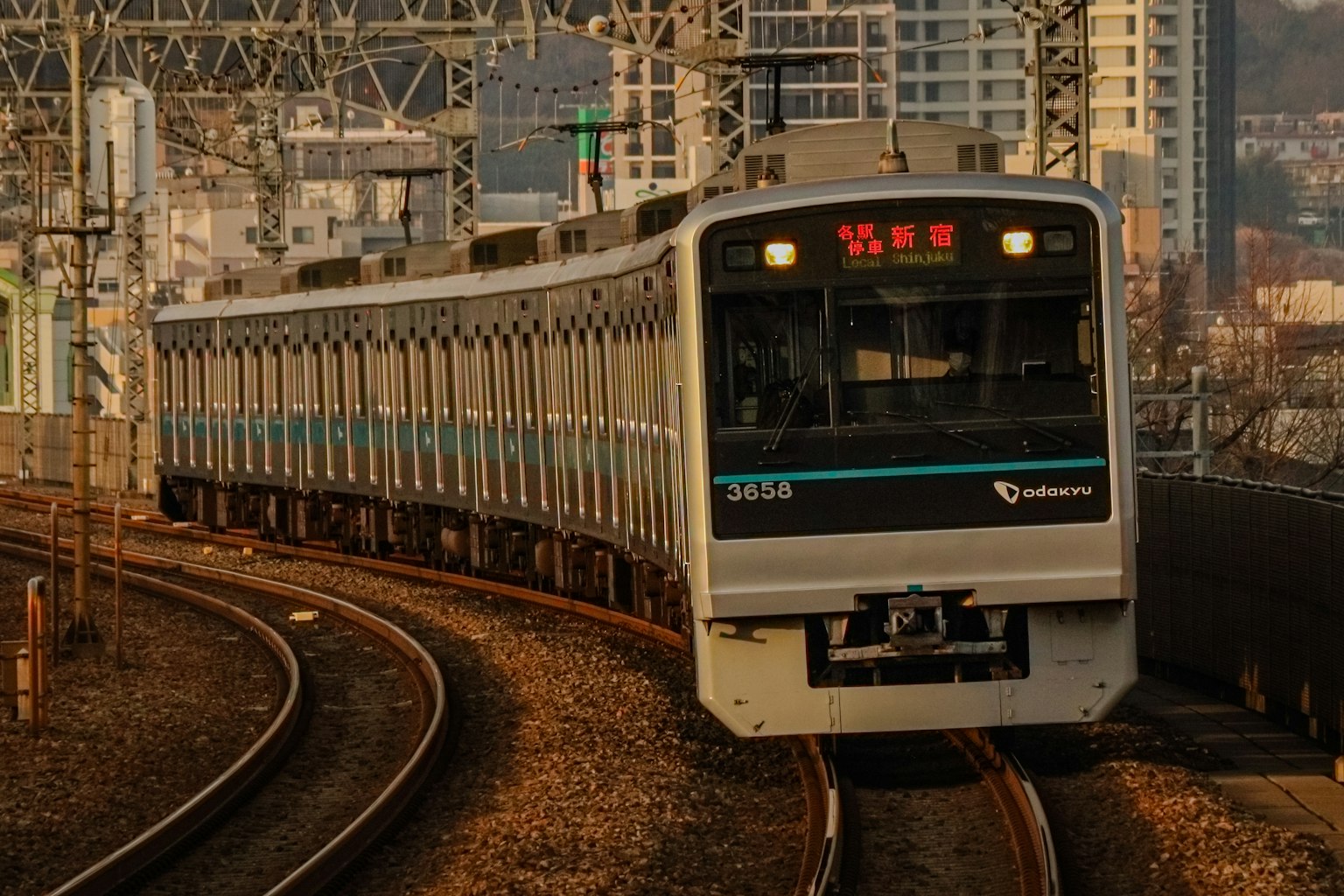 Treno argento che curva con sfondo urbano