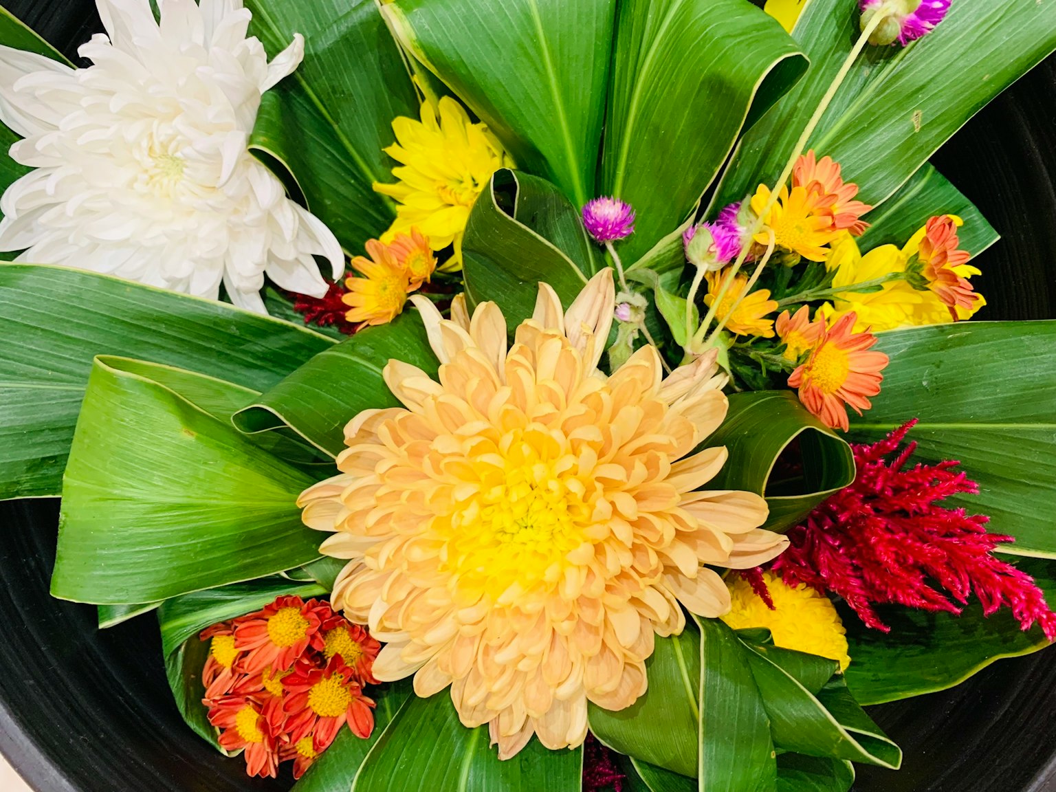 Susunan bunga dan daun yang indah dengan krisan kuning dan bunga kecil berwarna-warni