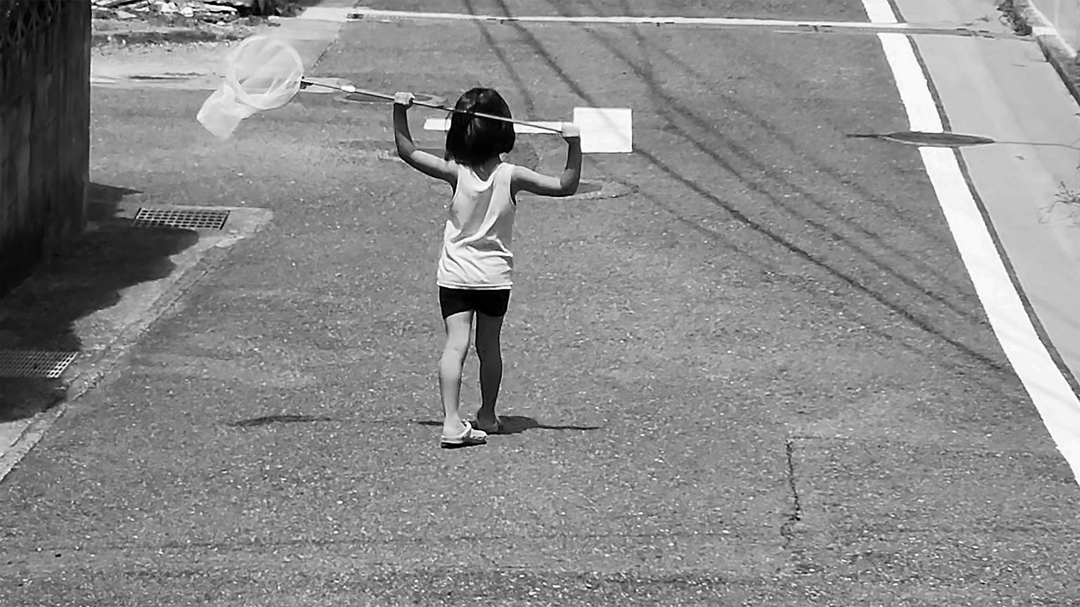 Un bambino che cammina con una rete su una strada in bianco e nero