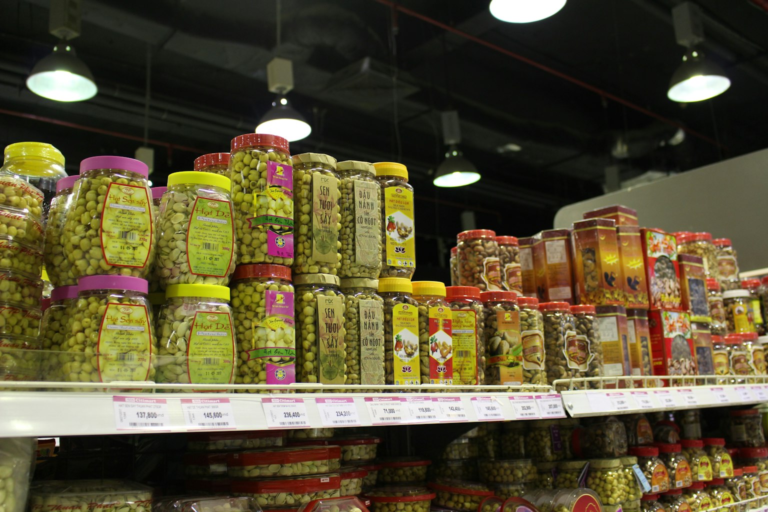 Vari barattoli di olive allineati su uno scaffale di supermercato