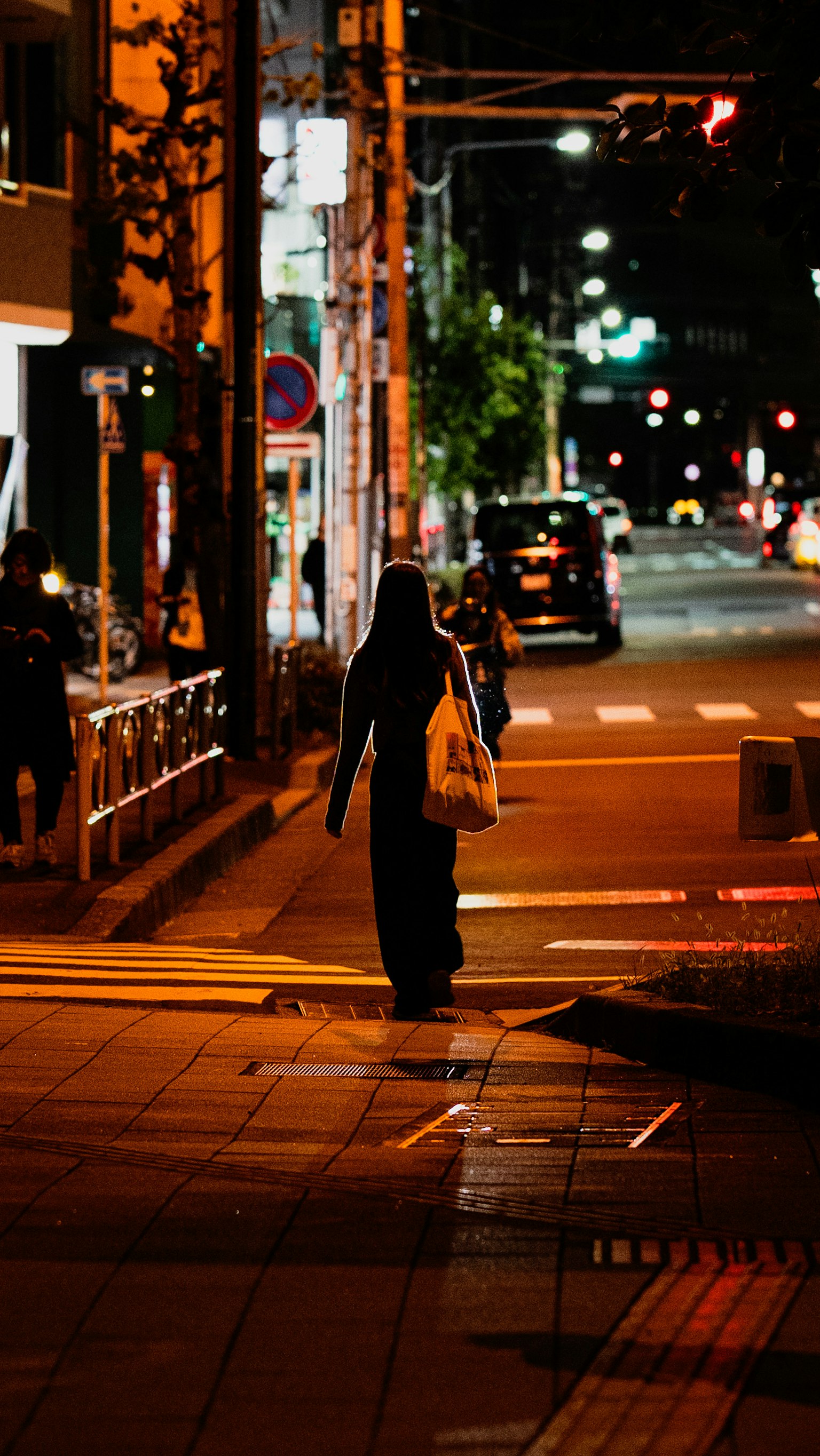 夜の街を歩く人物のシルエットと明かりのコントラスト
